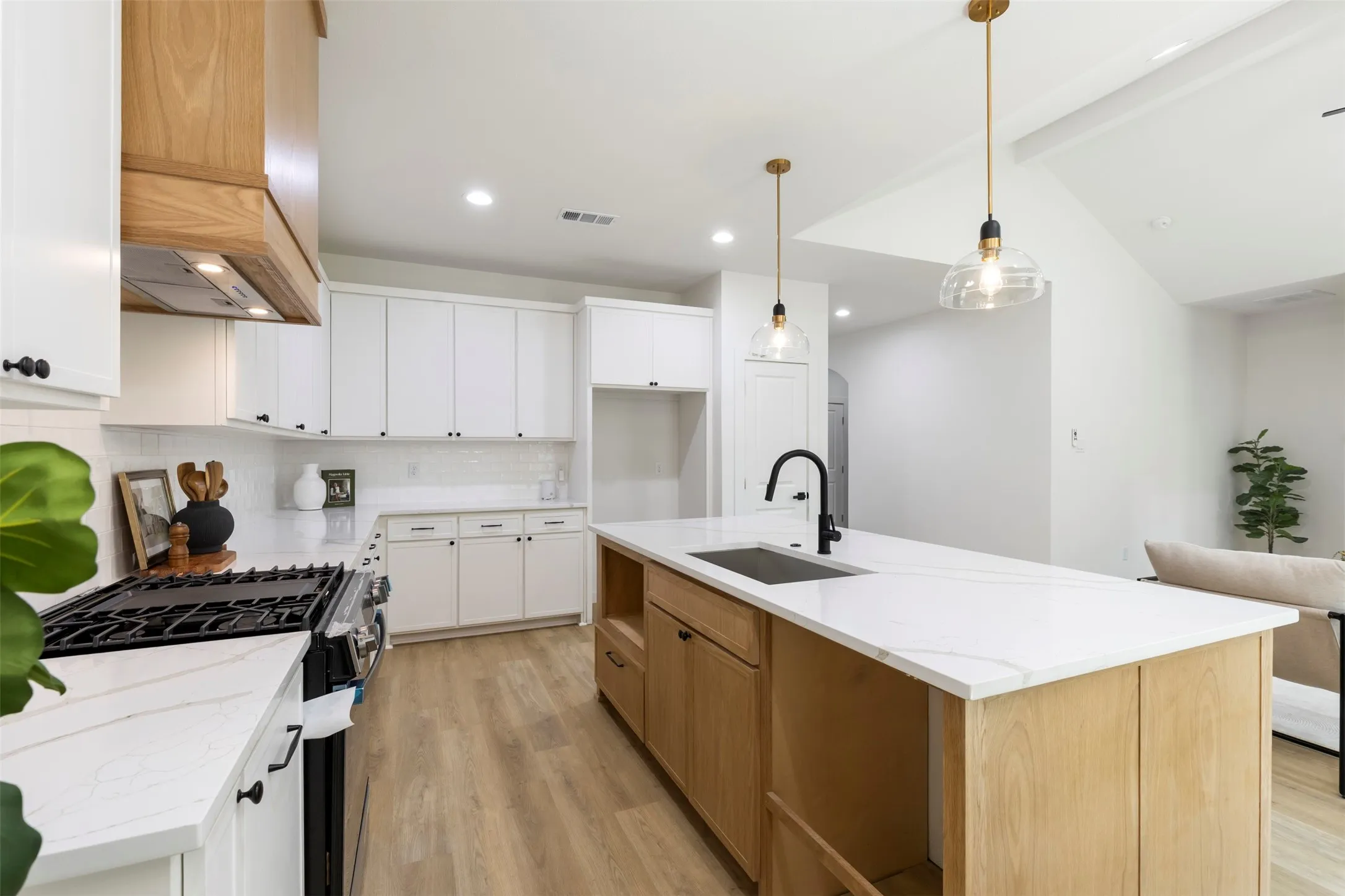 Contemporary kitchen featuring white cabinetry, a natural wood-finish kitchen island with a dark basin sink, white countertops, and wood-finish flooring