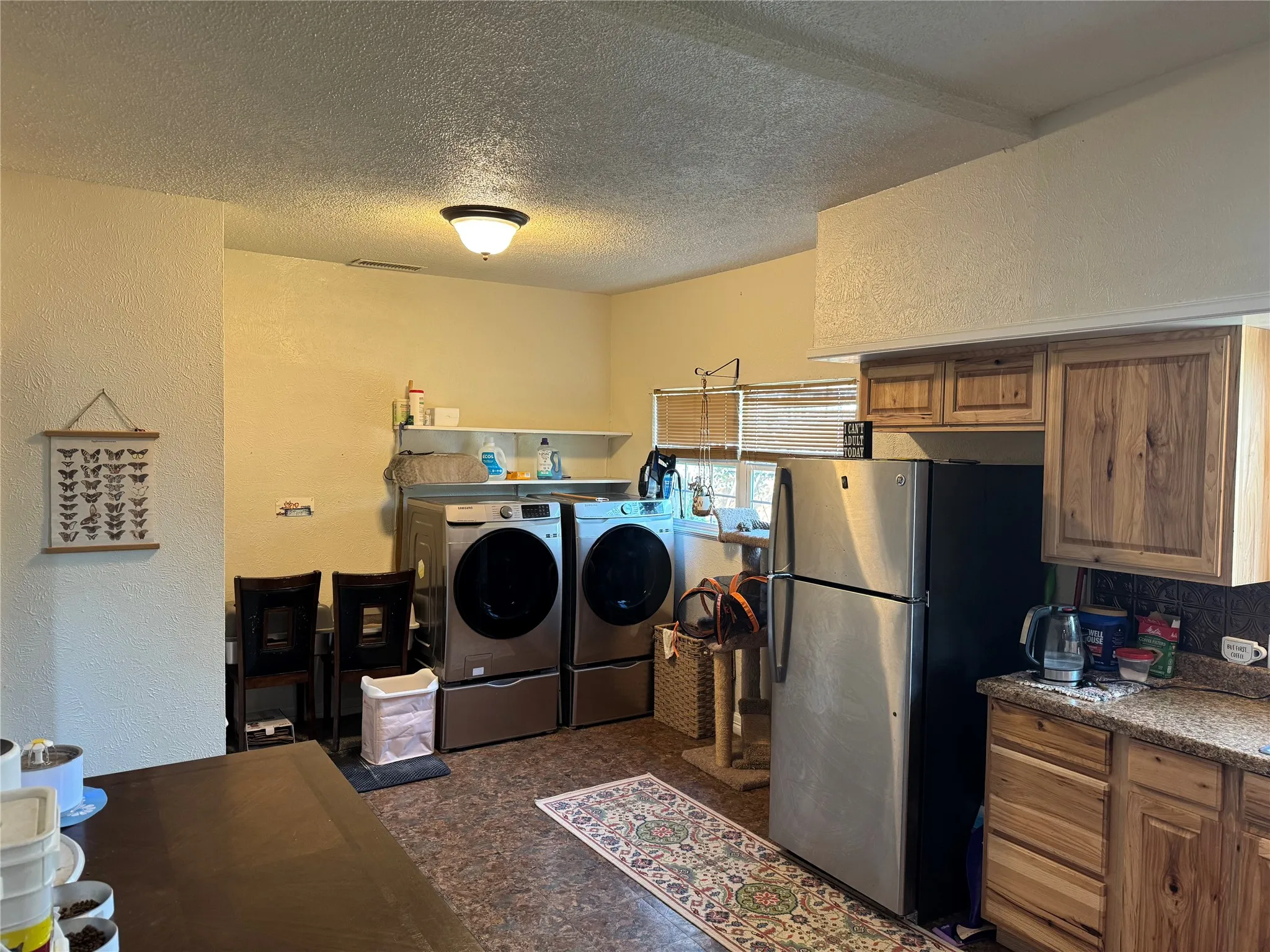 Washroom featuring a textured wall, a textured ceiling, and washing machine and clothes dryer