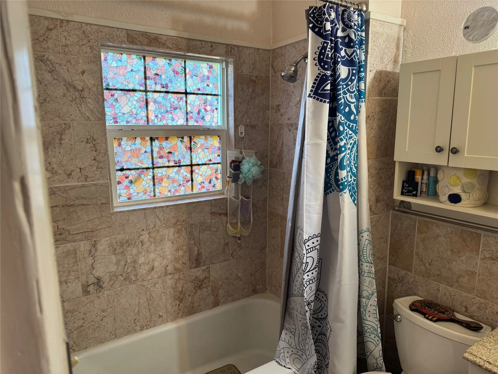 Bathroom with shower / tub combo and tile walls