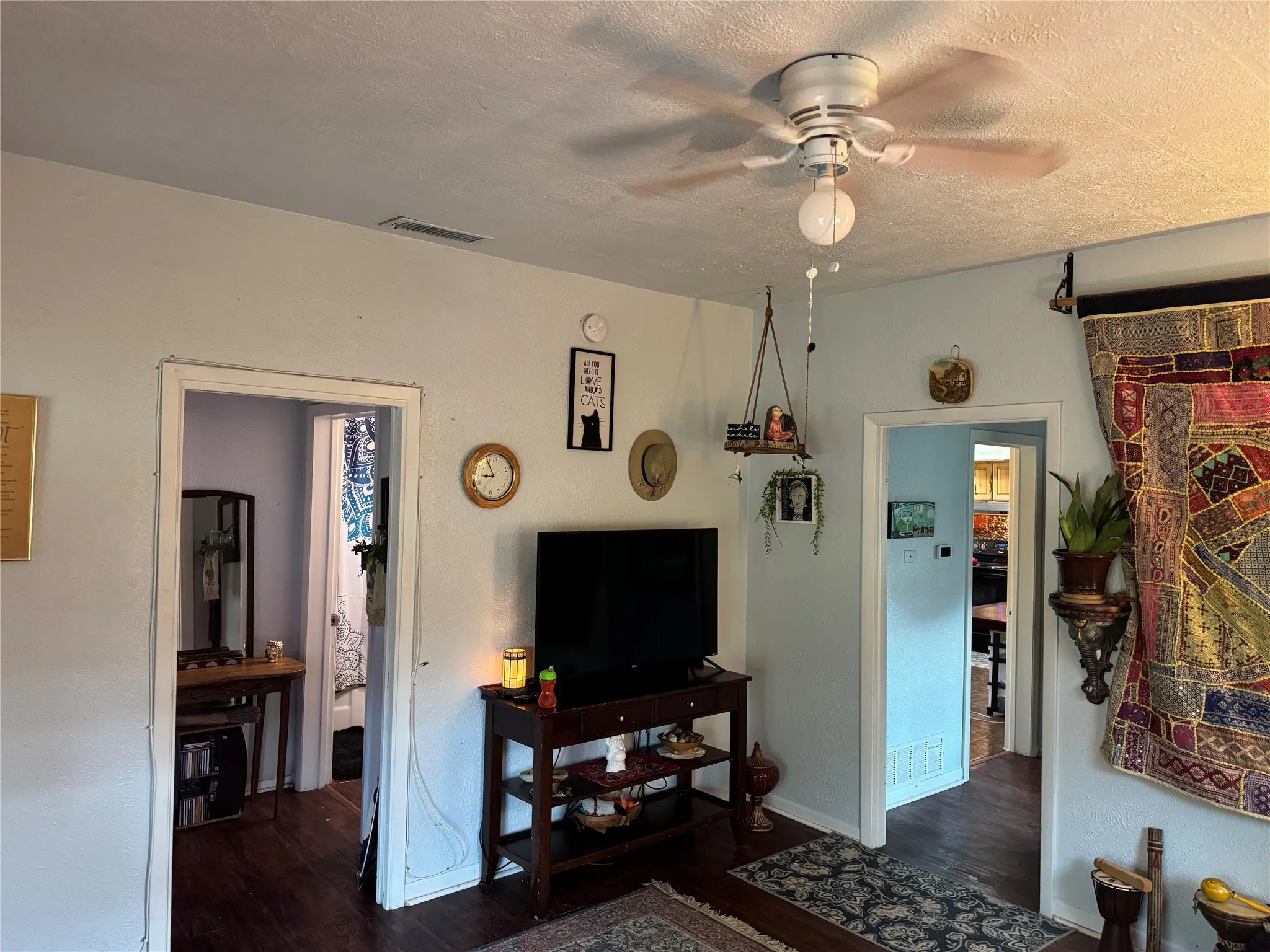 Living room with dark wood finished floors, a ceiling fan, and a textured ceiling