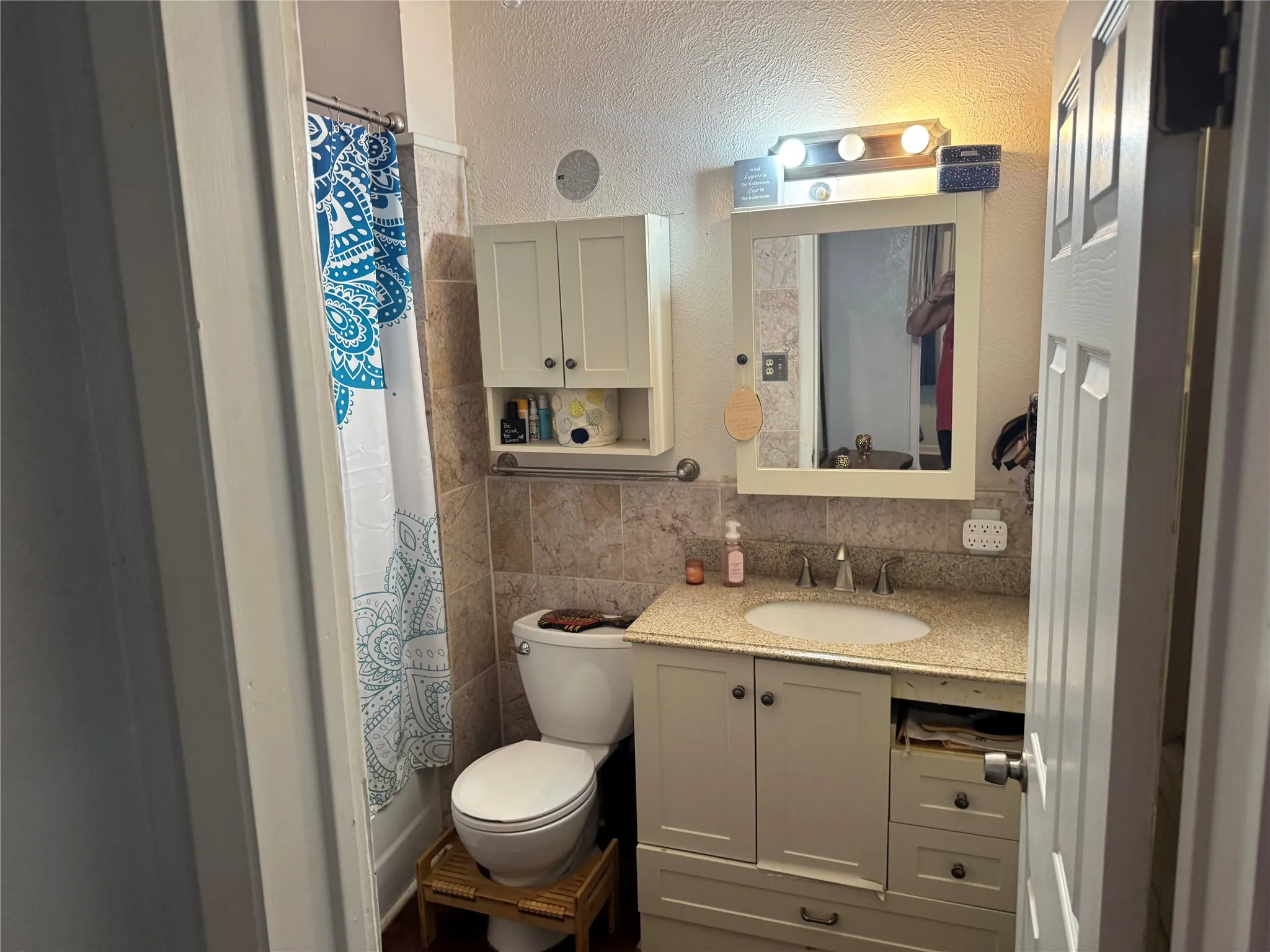Full bath with a textured wall, vanity, and tile walls