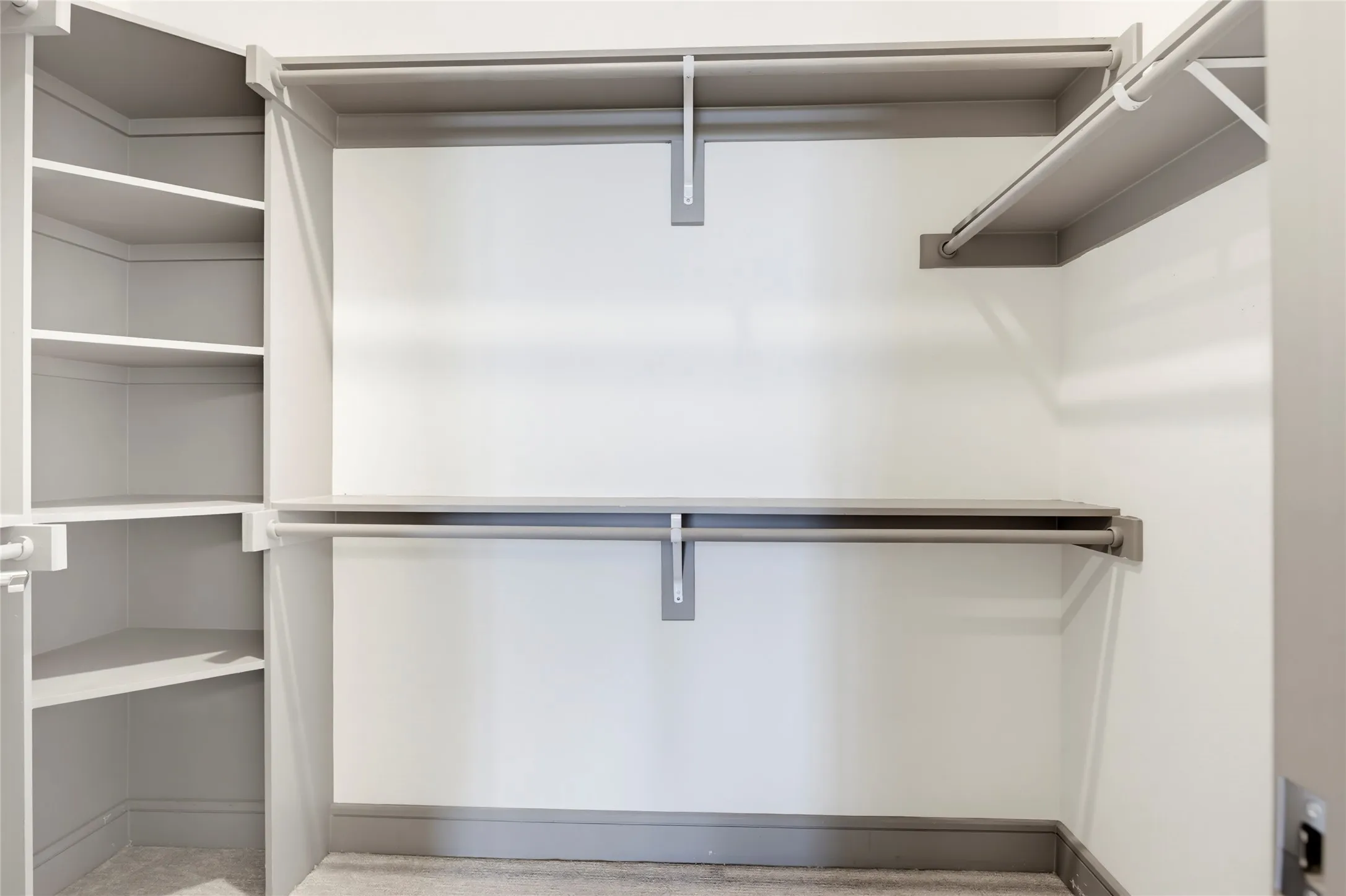 Built-in shelving with multiple storage levels, integrated hanging rods, and carpeted flooring
