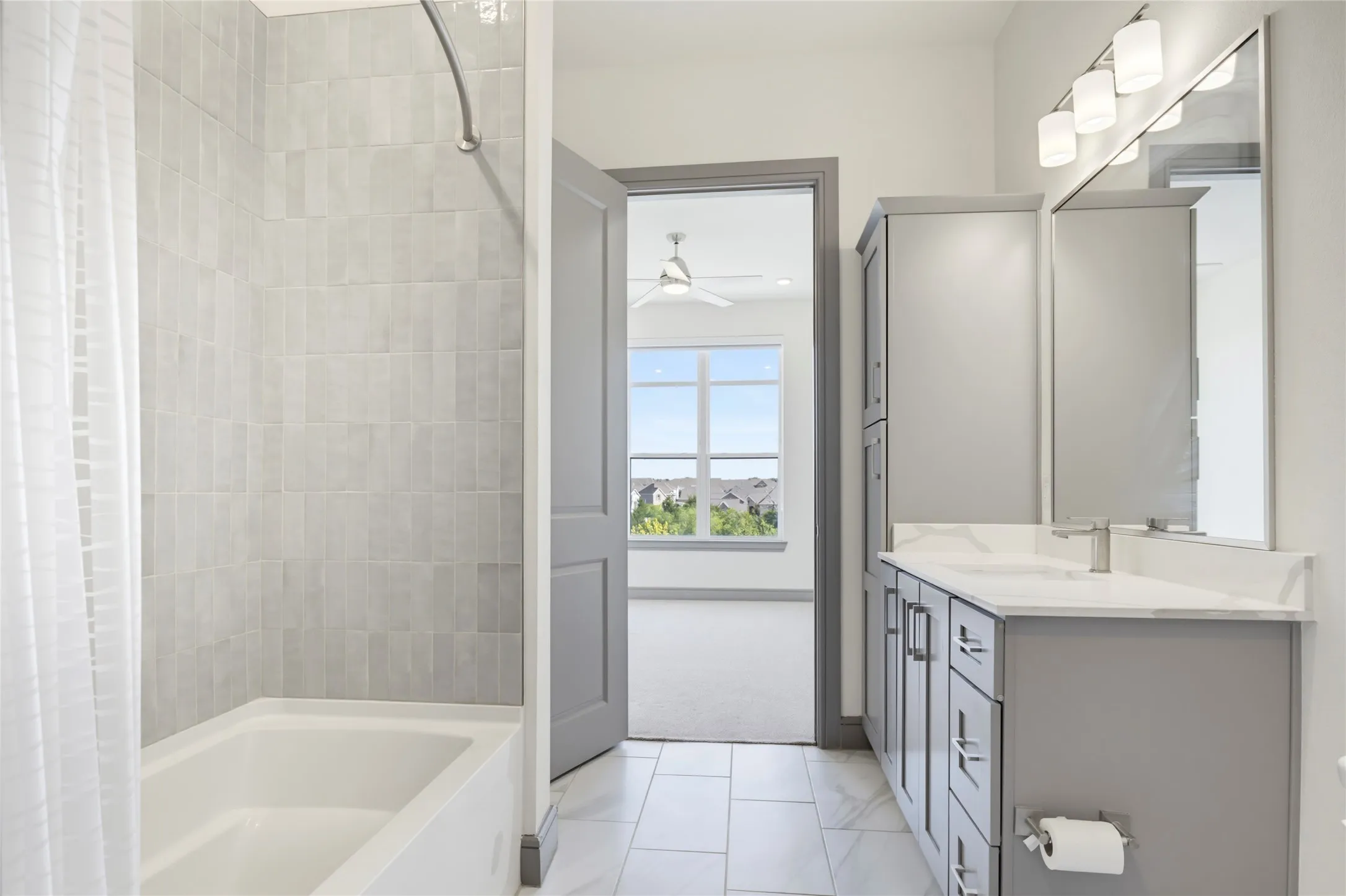 Modern bathroom featuring a tiled tub/shower combination, a vanity with a countertop and undermount sink, and tiled flooring