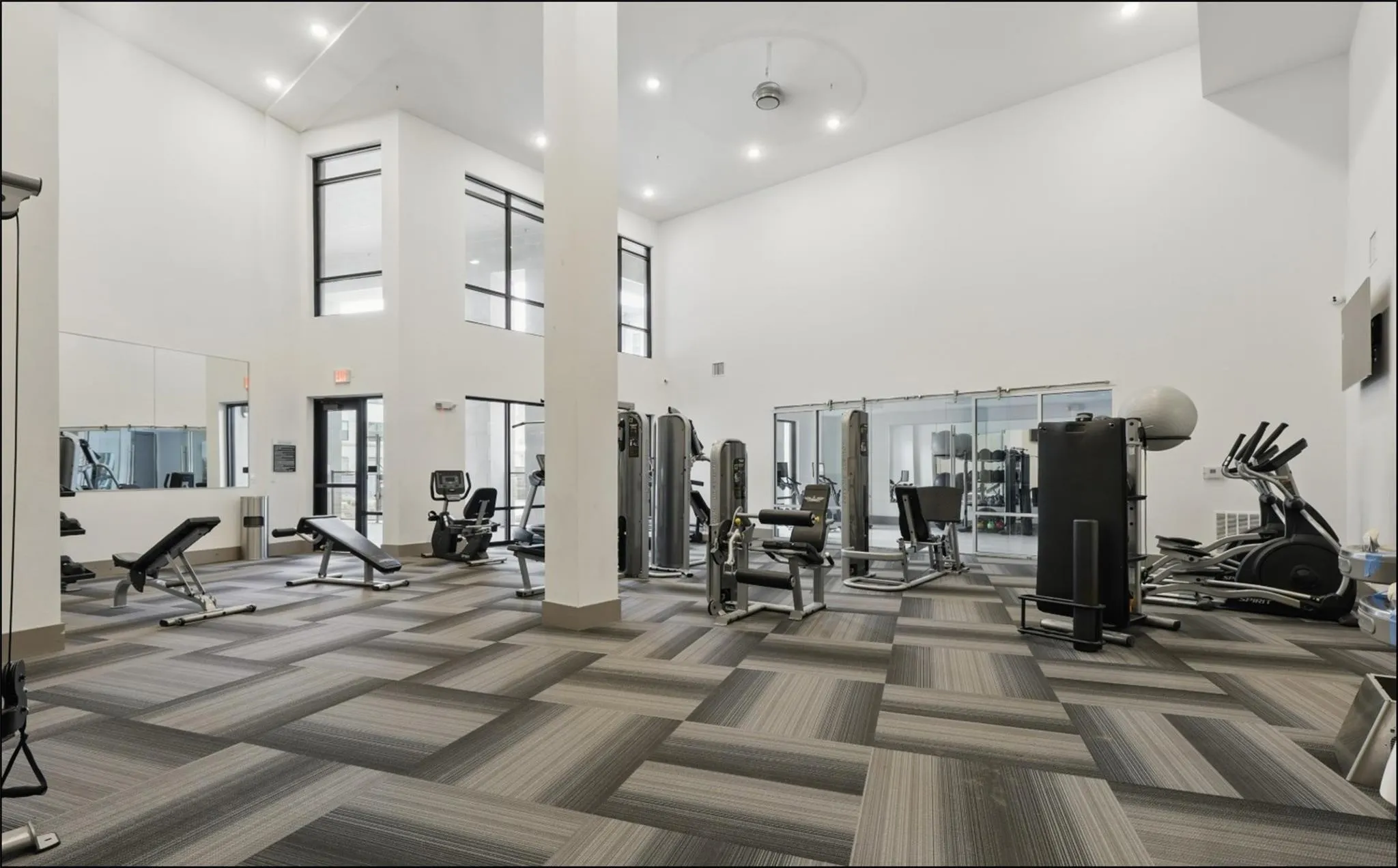 Fitness center featuring high ceilings, large windows, recessed lighting, patterned carpet flooring, and a variety of exercise equipment