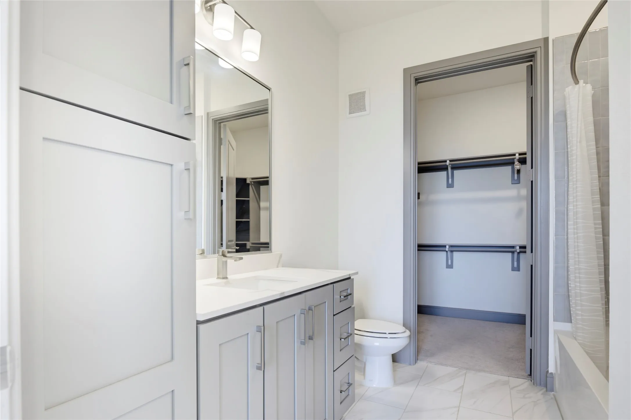 Light gray vanity with brushed nickel hardware, white countertop, and rectangular undermount sink