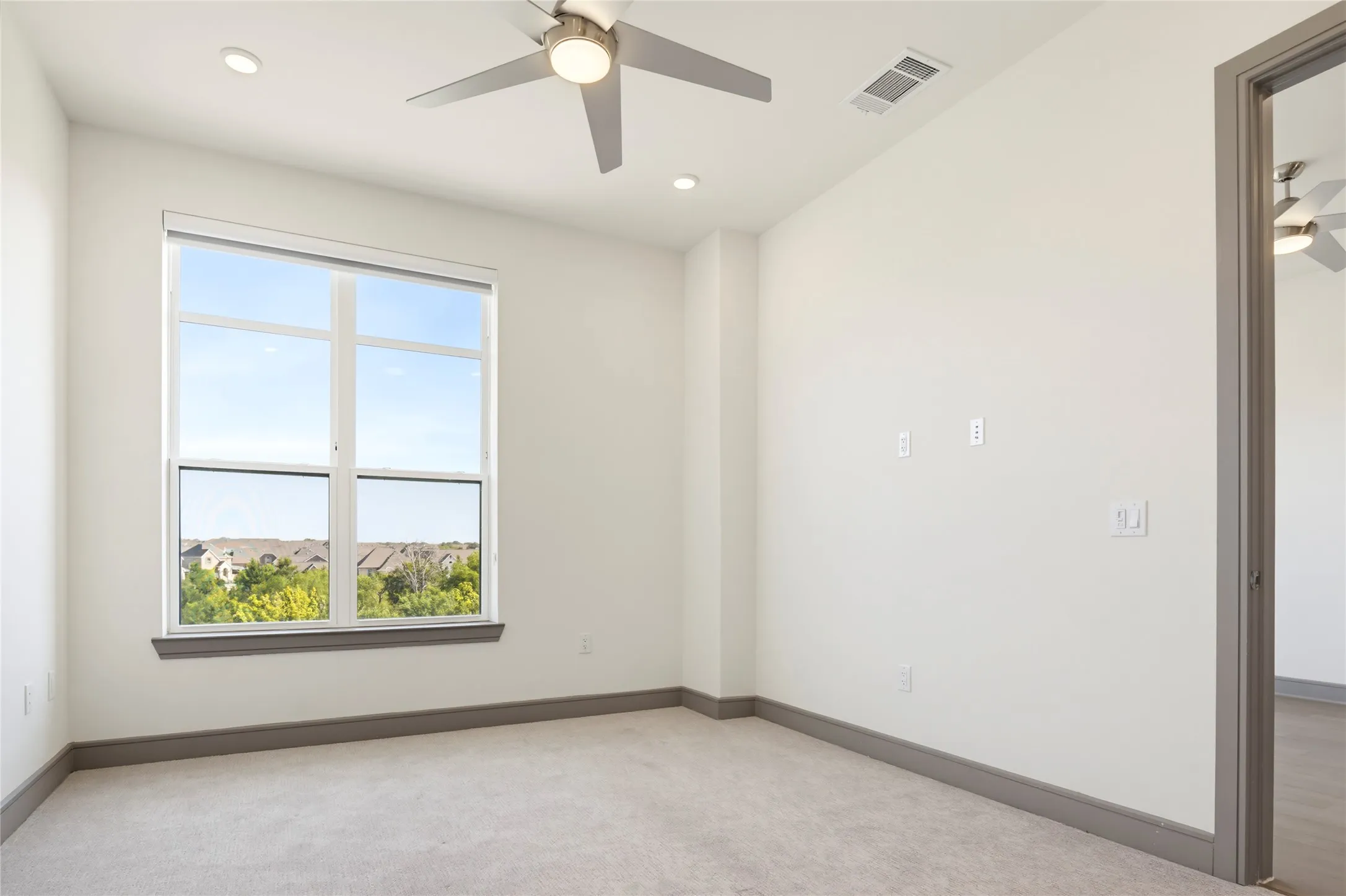 Neutral-toned carpeting paired with a modern ceiling fan and recessed lighting