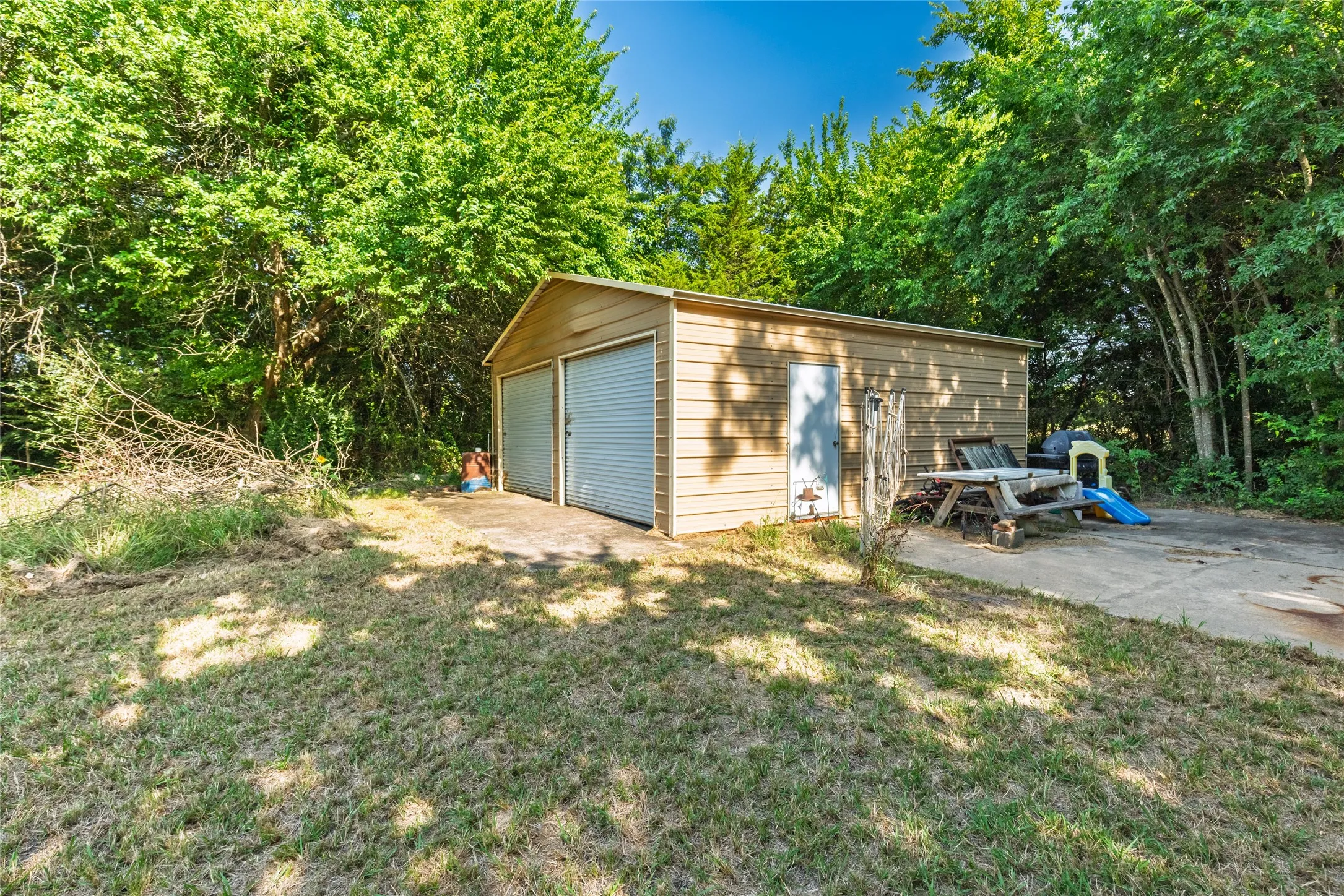 Detached utility building with two roll-up doors, a side entry door, and a concrete pad