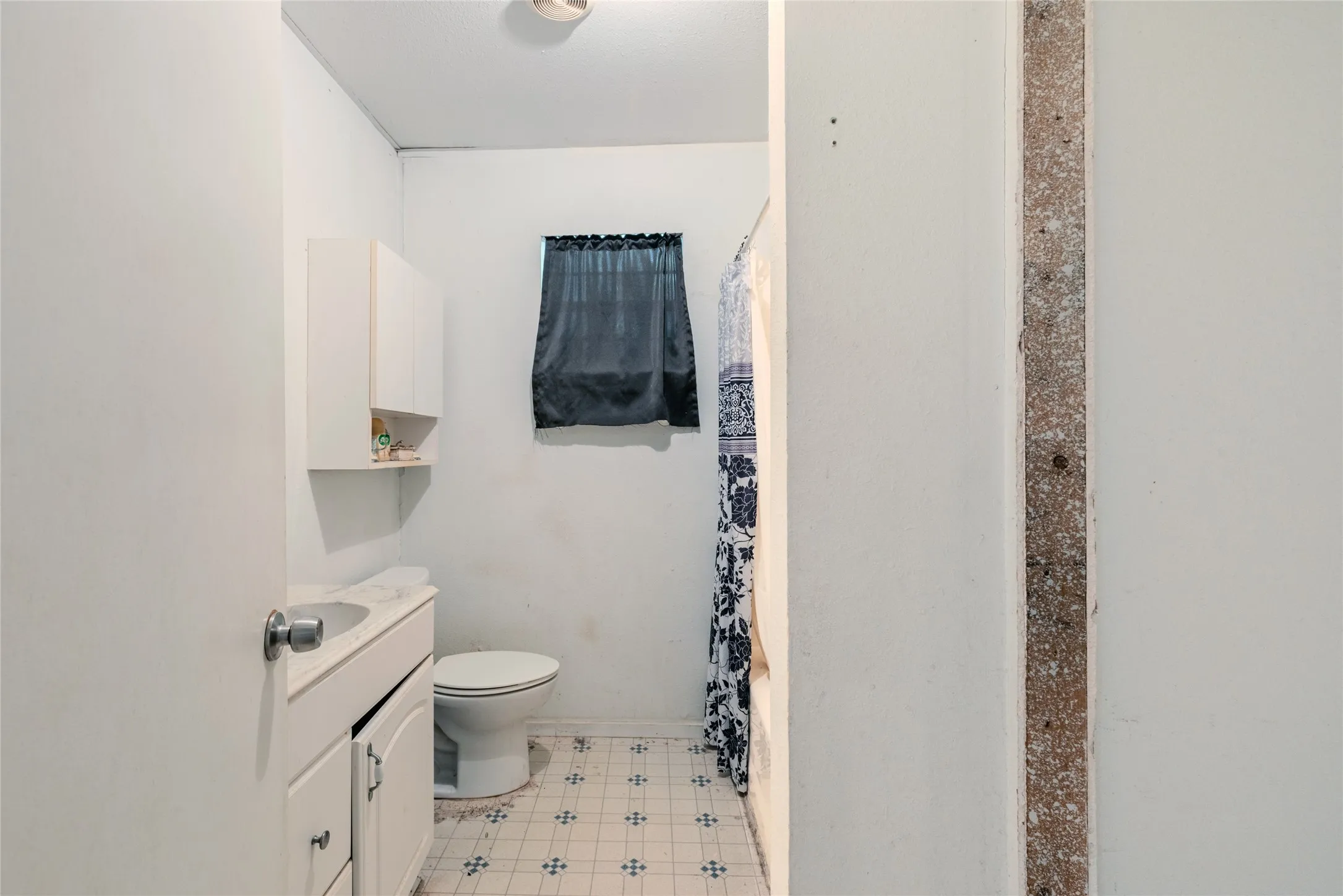 Bathroom featuring a vanity with a drop-in sink, built-in cabinetry, and patterned floor tiling