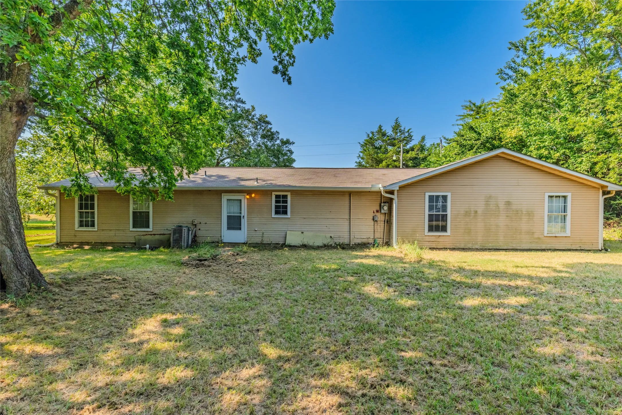 Charming single-story residence featuring a spacious front elevation with multiple windows, neutral exterior siding, and a covered entry
