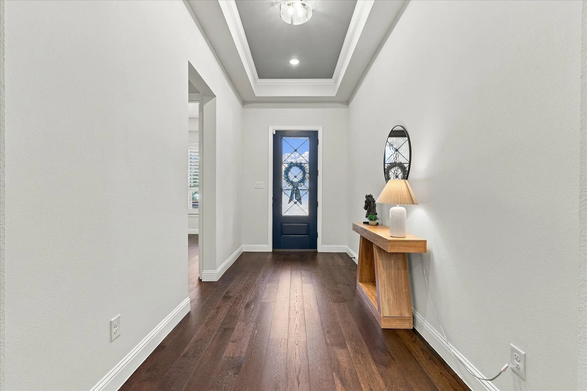 Entry foyer with tray ceiing and engineered hardwood flooring.  Office or Bedroom and full bath in the left alcove