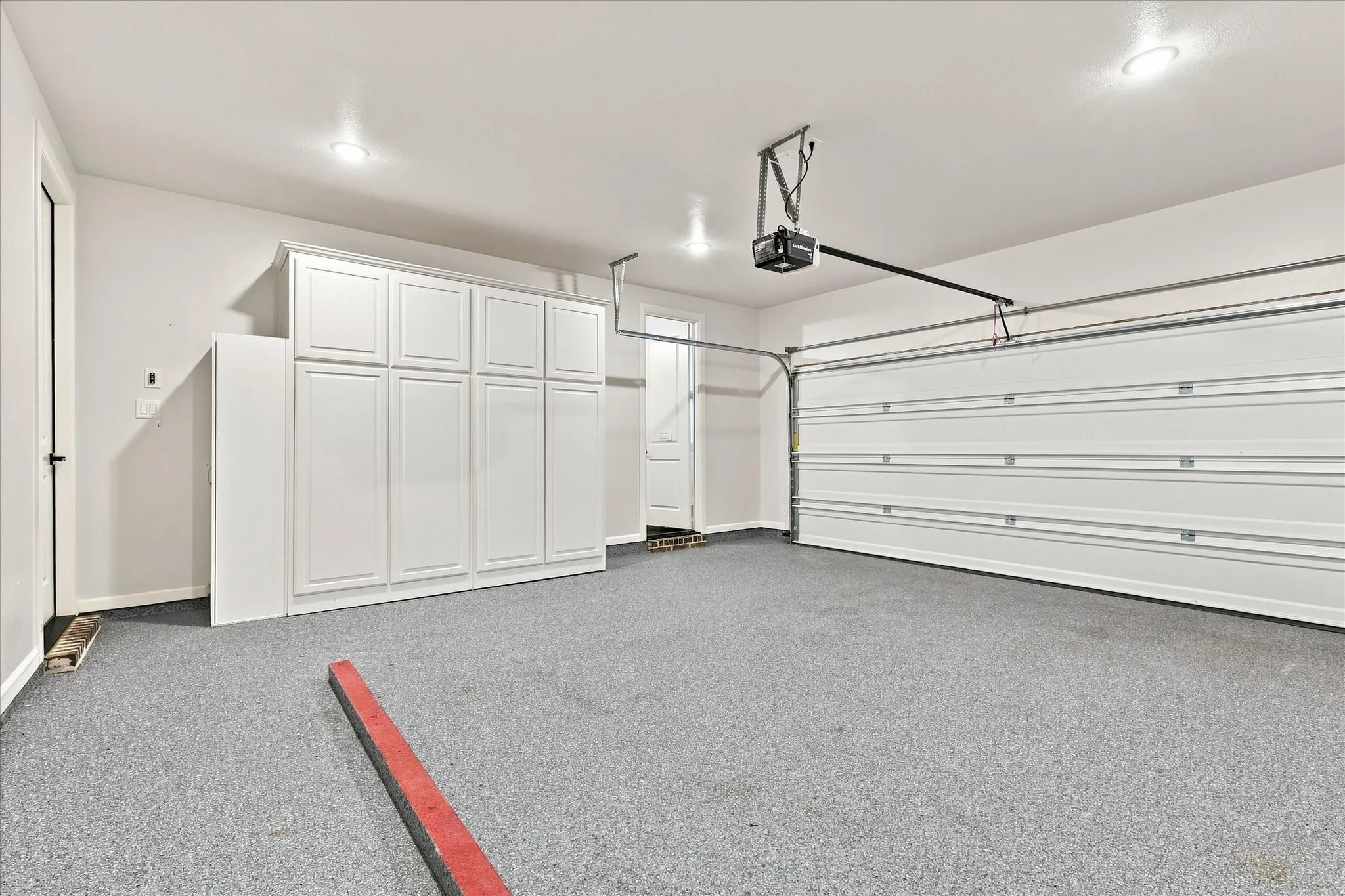 Beautiful epoxy flooring, built-in storage, and door to the upstairs bonus room ahead on the right.  Note how comfortable the temperature is.  The attic is foam incapsulated which makes a tremendous difference!