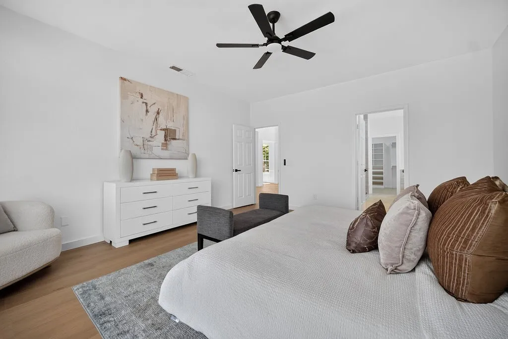 Spacious primary bedroom featuring hardwood flooring, a ceiling fan with integrated lighting, and abundant natural light from multiple windows