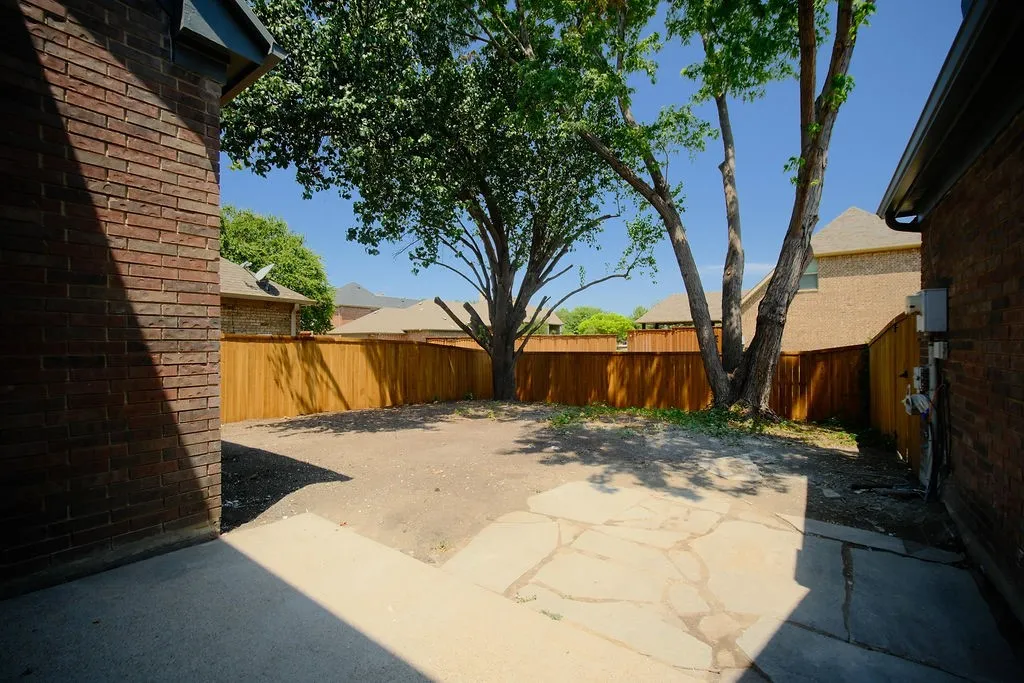 Private backyard featuring a new wood fence, mature trees, and a concrete patio