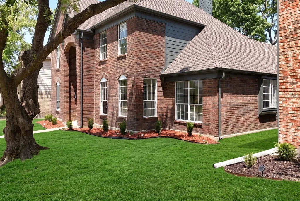 Brick exterior with gray siding accents, an arched entryway, and white-framed windows