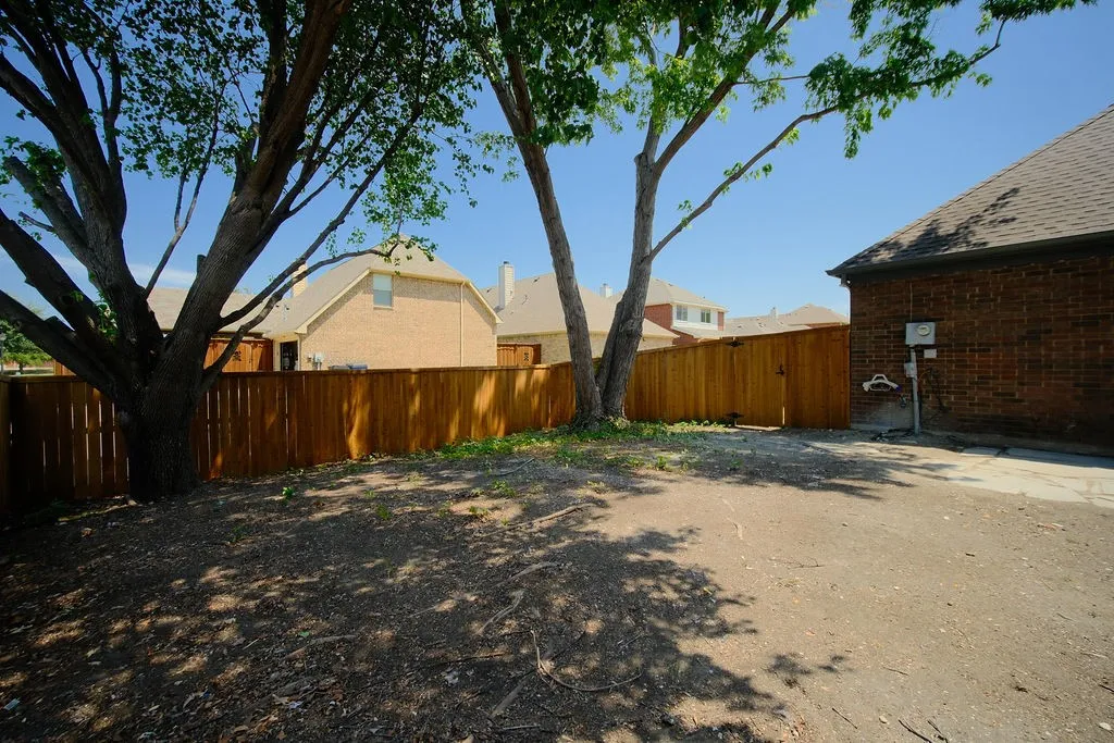 Private backyard with wood fencing, mature trees, and a paved concrete section