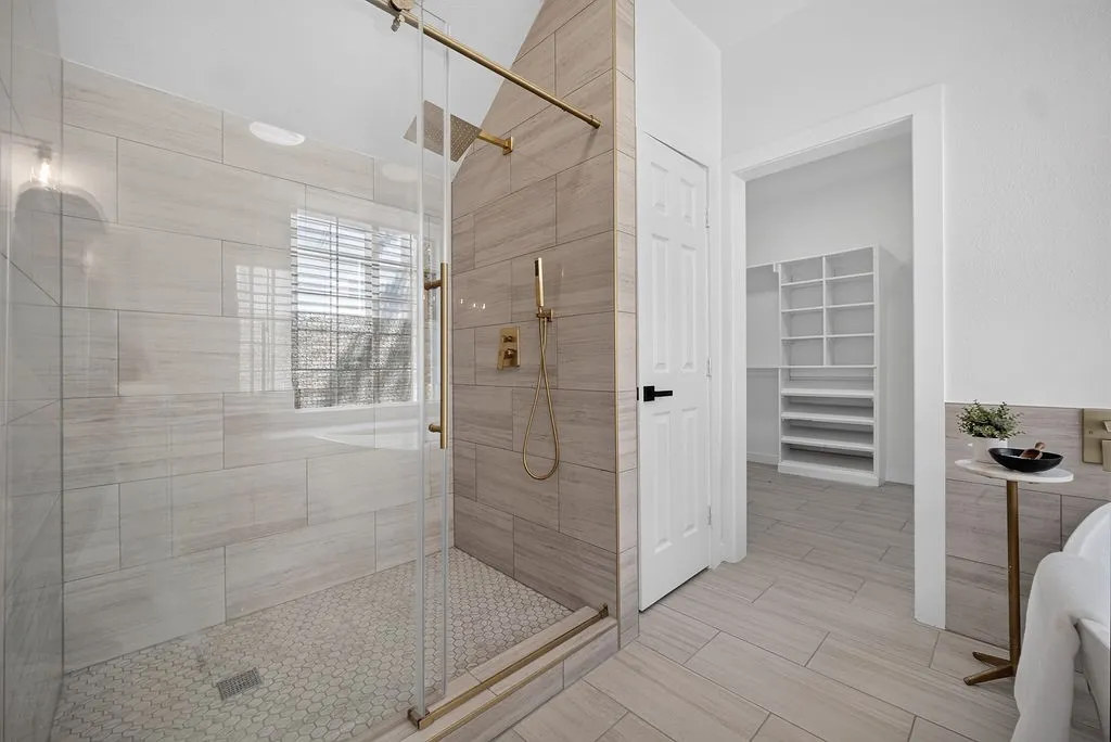 Spa-inspired primary bathroom featuring a frameless glass-enclosed walk-in shower with linear drain, dual showerheads, and brushed nickel fixtures
