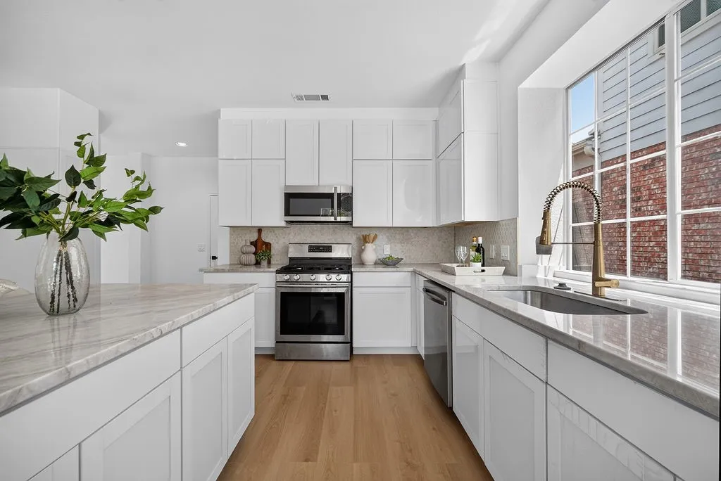 Modern kitchen featuring white cabinetry, stainless steel appliances, quartz countertops, and a center island