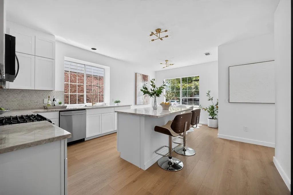 Modern kitchen featuring white cabinetry, stainless steel appliances, and a substantial island with waterfall-edge countertop