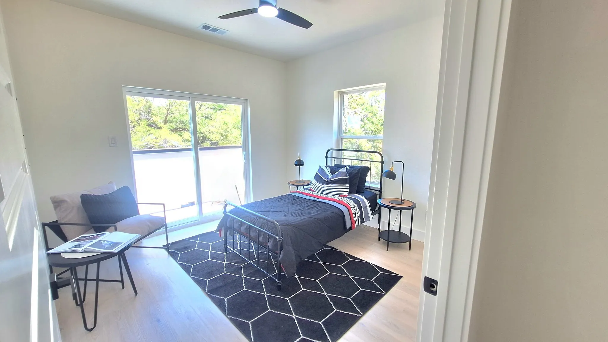 Wood-finish flooring, white walls, and a black ceiling fan with integrated lighting