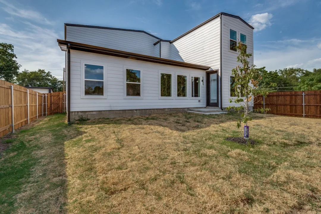 Contemporary exterior with white siding and dark trim, featuring multiple windows and a glass-paned door