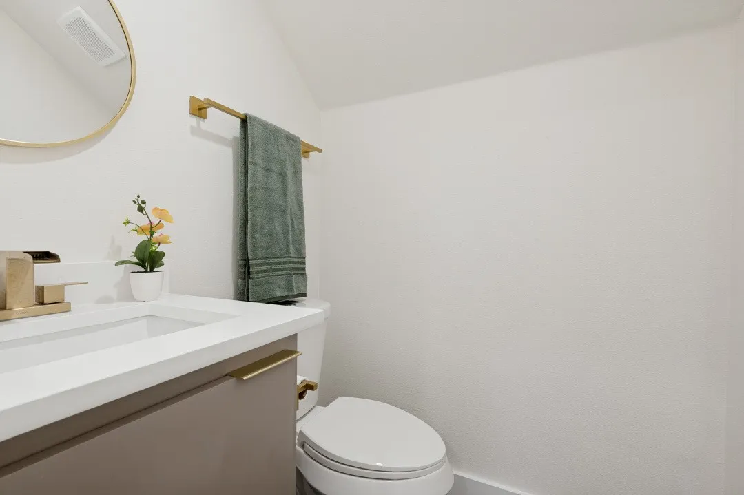 Vanity with an integrated rectangular sink, gold-finish faucet, and a contemporary gold-framed circular mirror