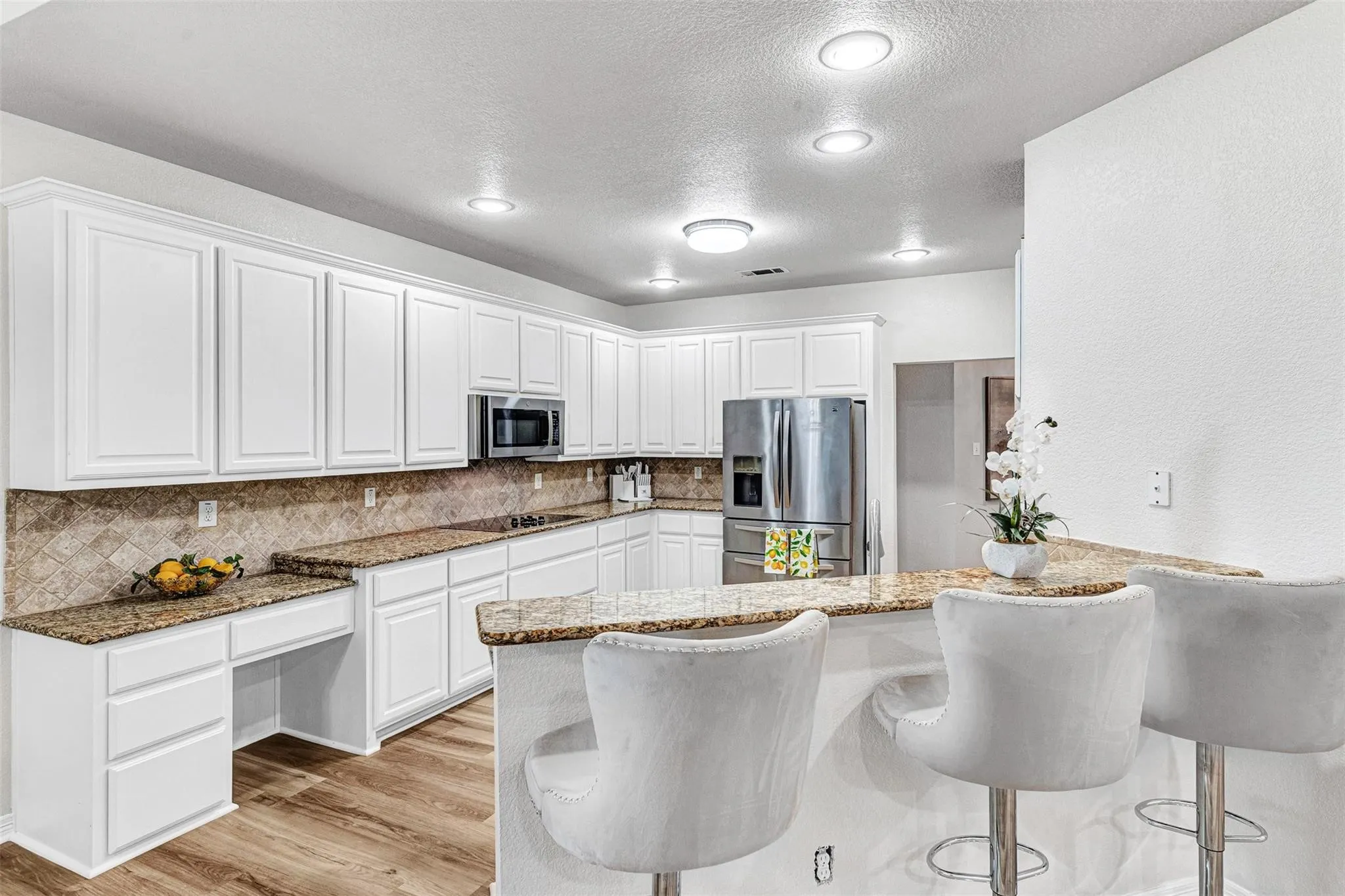 Kitchen featuring white shaker-style cabinetry, granite countertops, a built-in microwave, and wood-finish flooring
