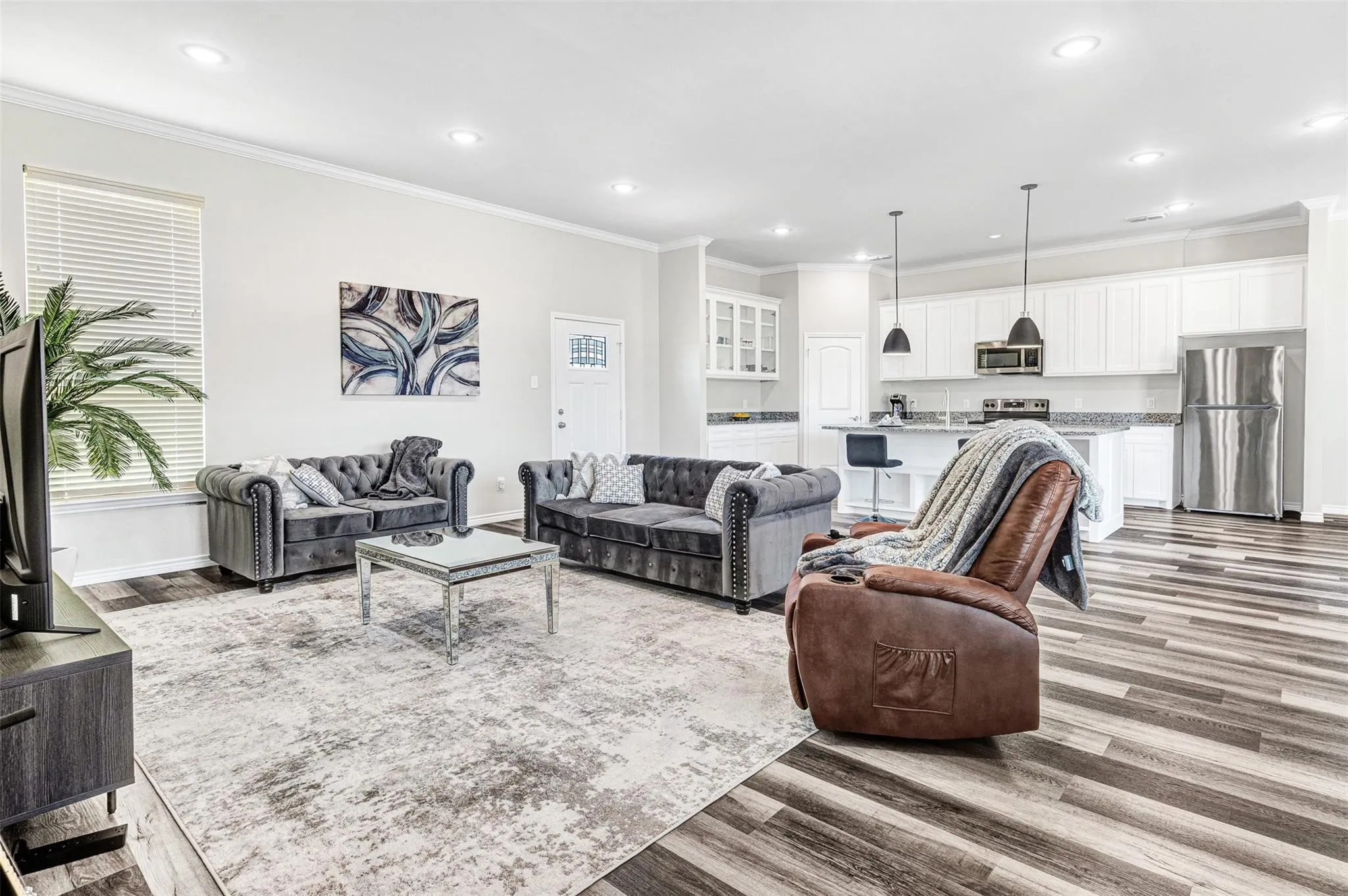 Open-concept living space with wood-finish flooring, recessed lighting, and crown molding
