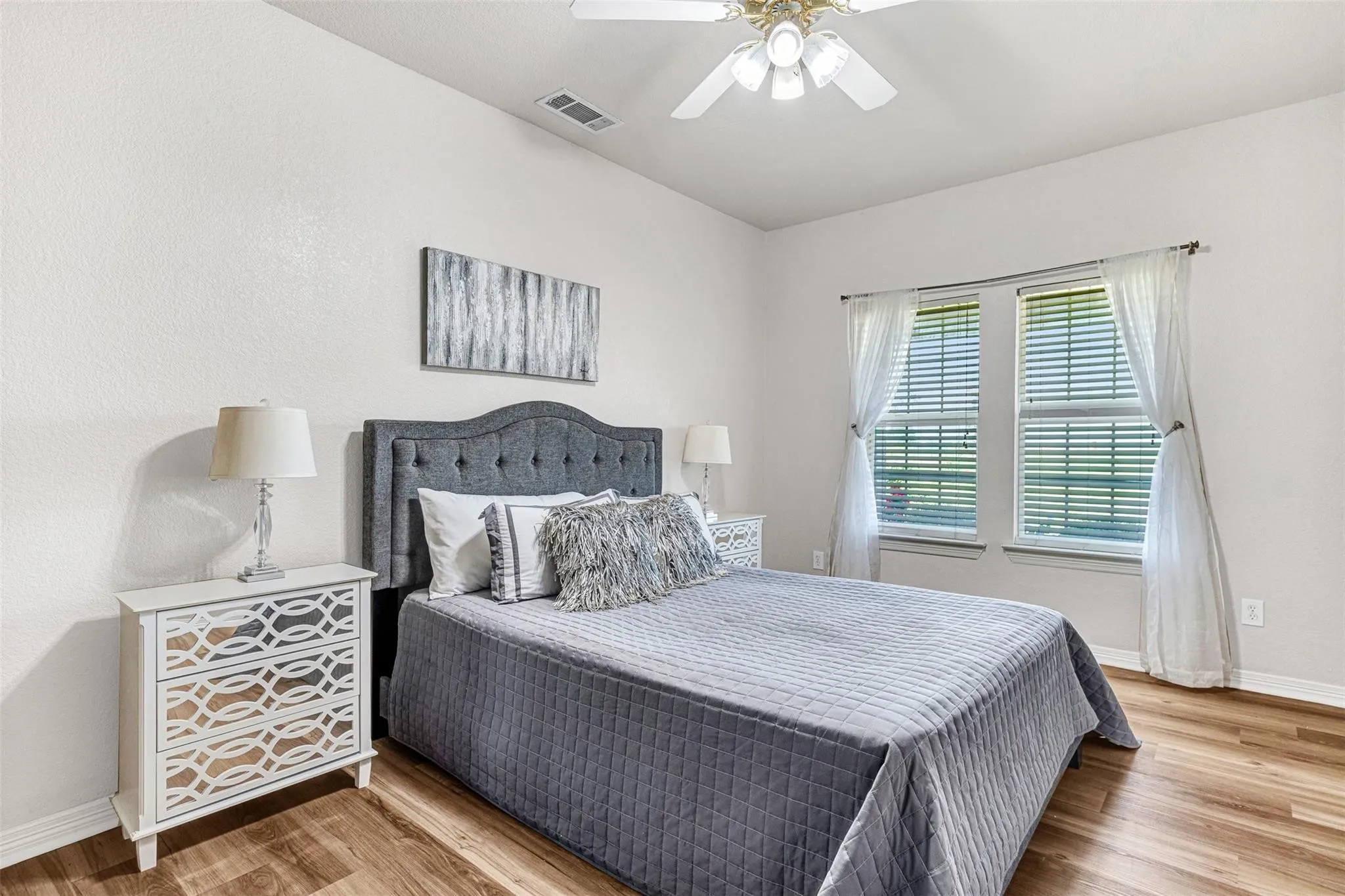Wood-finish flooring, white walls, and a ceiling fan with integrated lighting