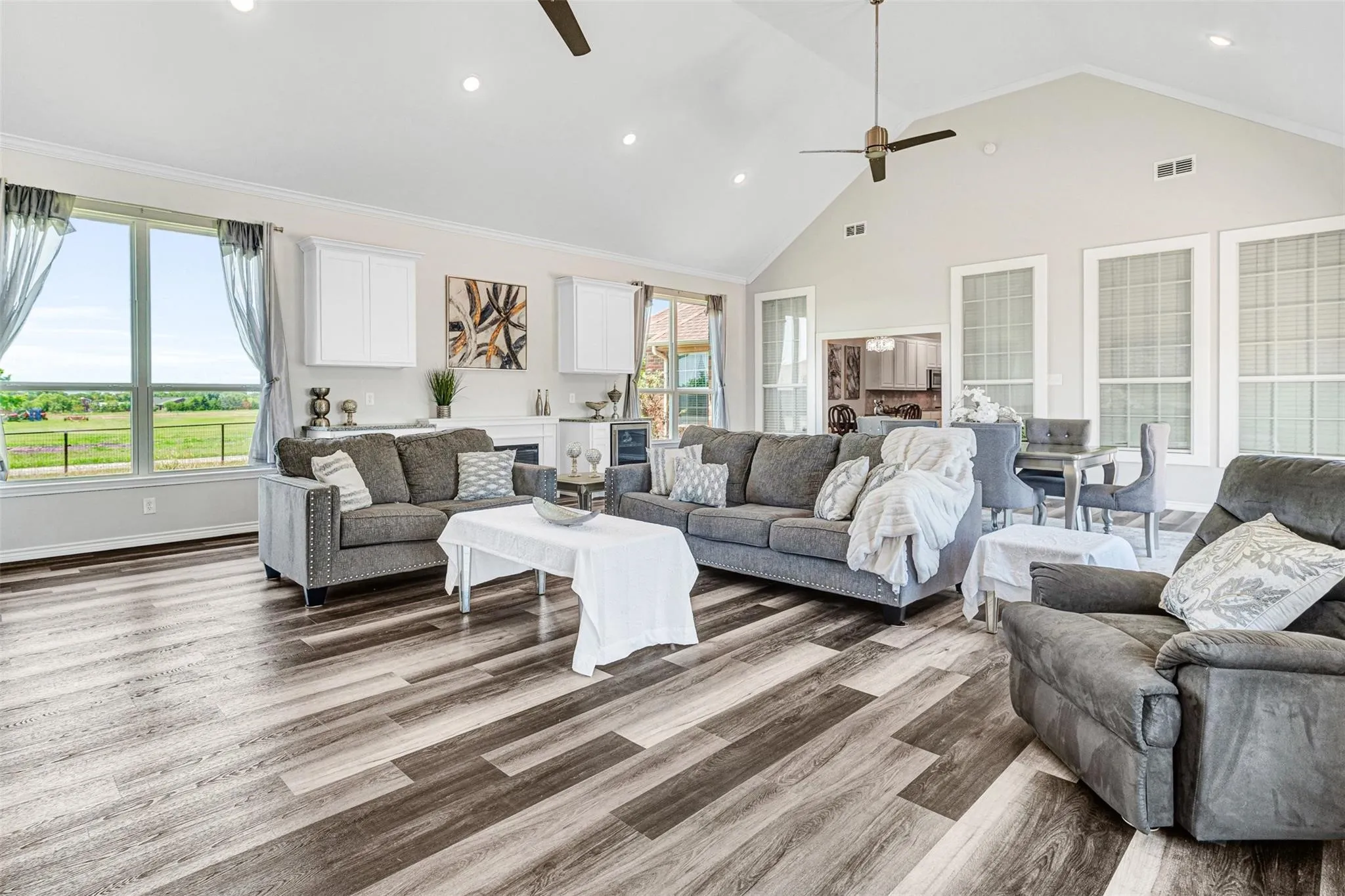 Spacious living area featuring vaulted ceilings, wood-finish flooring, recessed lighting, and large windows with transom elements