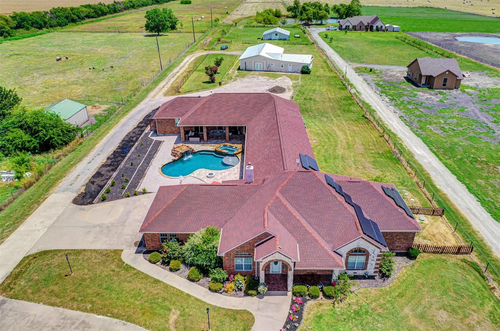 Sprawling single-story residence with a distinctive burgundy tile roof and curved architectural lines, situated on expansive grounds