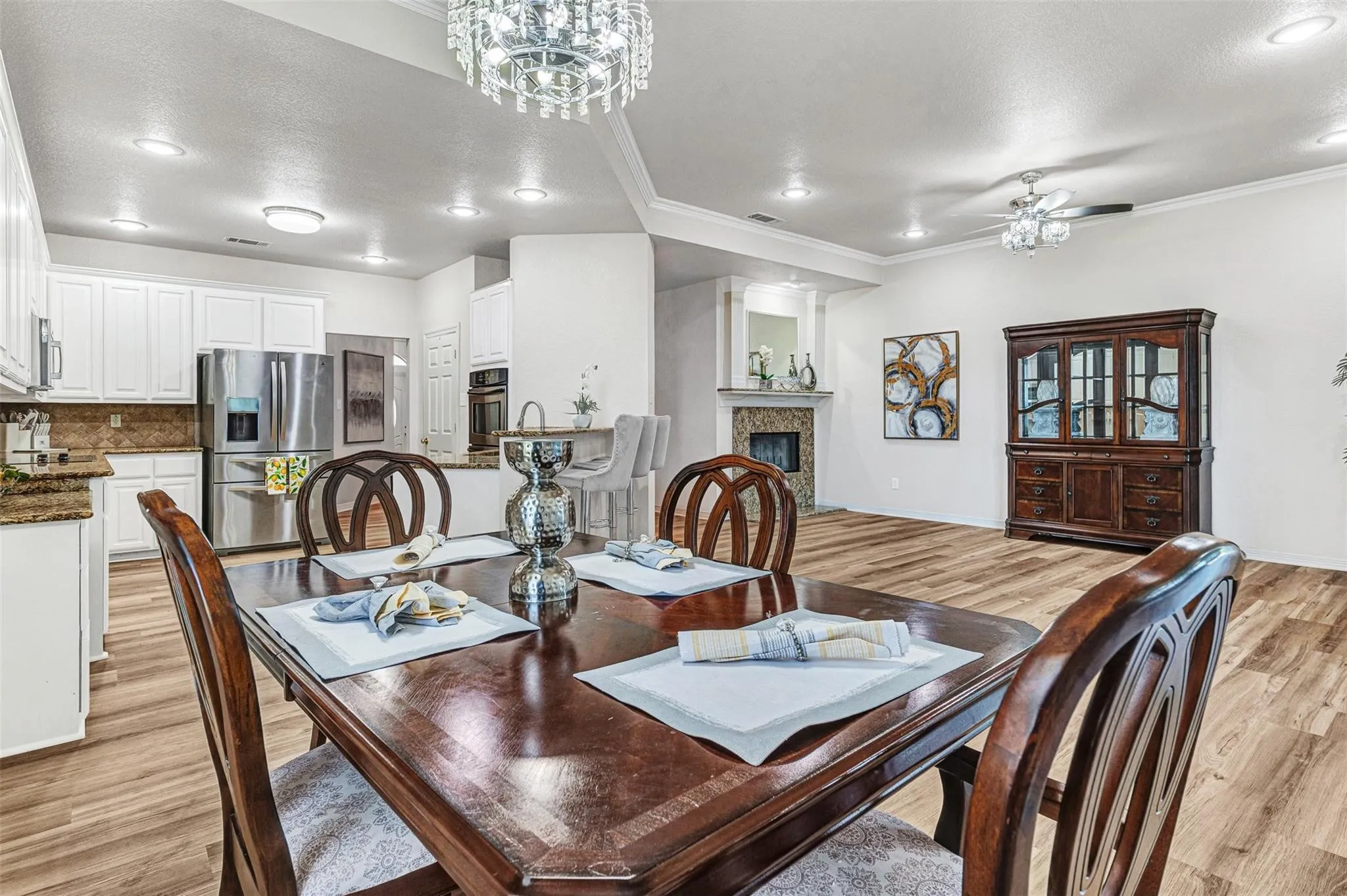Wood-finish flooring throughout, white cabinetry, recessed lighting, ceiling fan, and a stone-clad fireplace