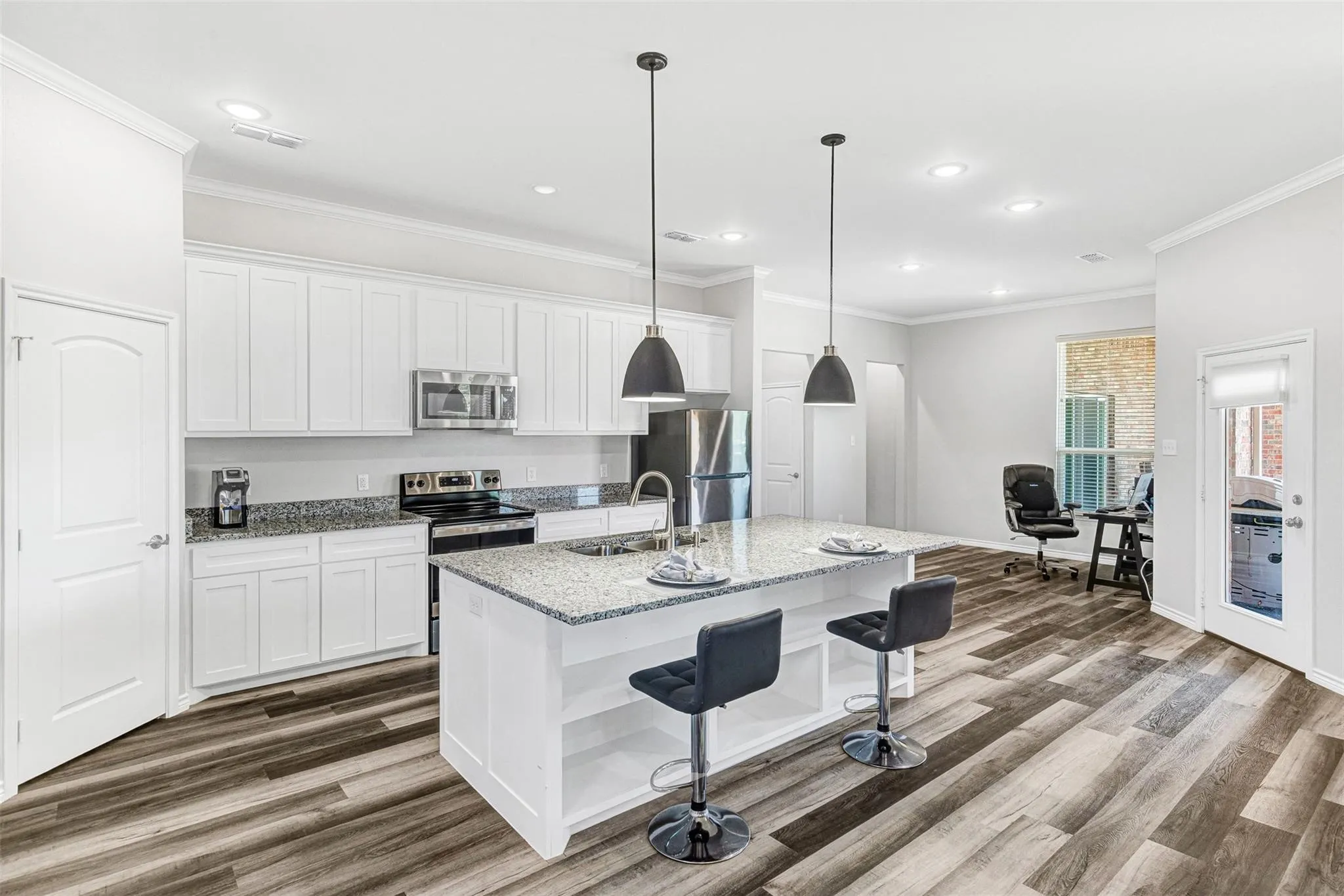 Kitchen featuring white cabinetry, granite countertops, stainless steel appliances, a center island with pendant lighting, and wood-finish flooring