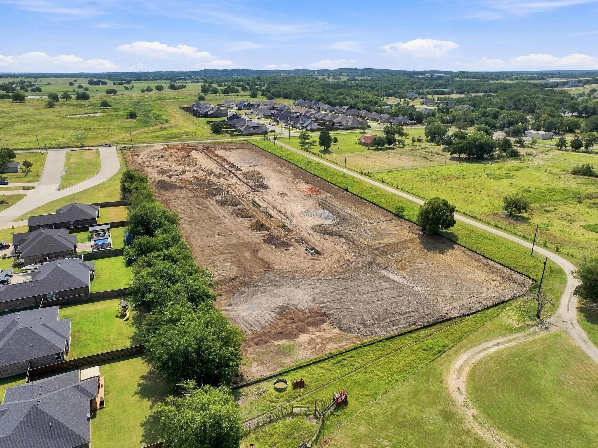 Cleared building lot bordered by established residences and natural landscape
