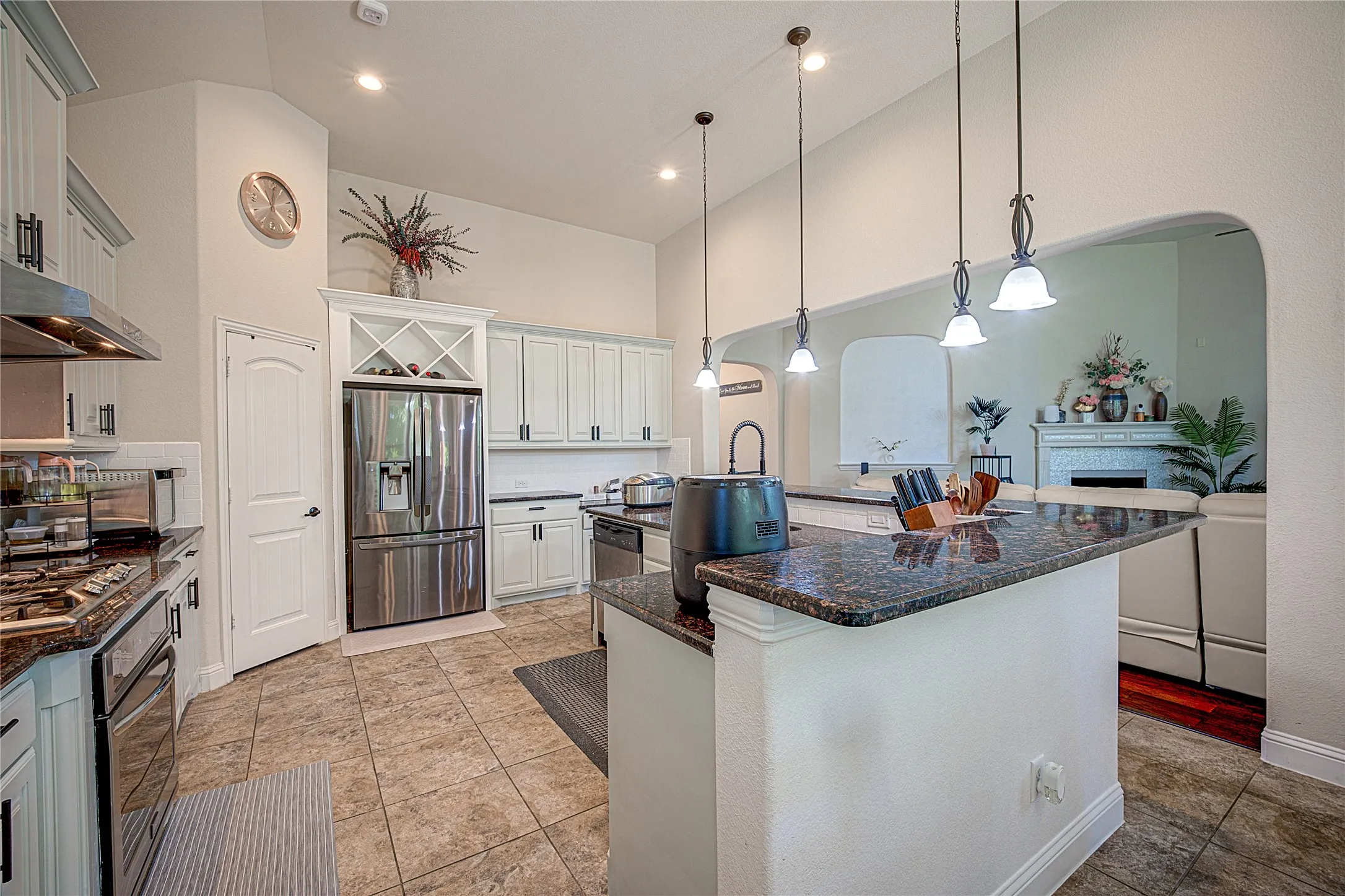 Kitchen featuring vaulted ceilings, recessed lighting, and a kitchen island with a stone-finish countertop