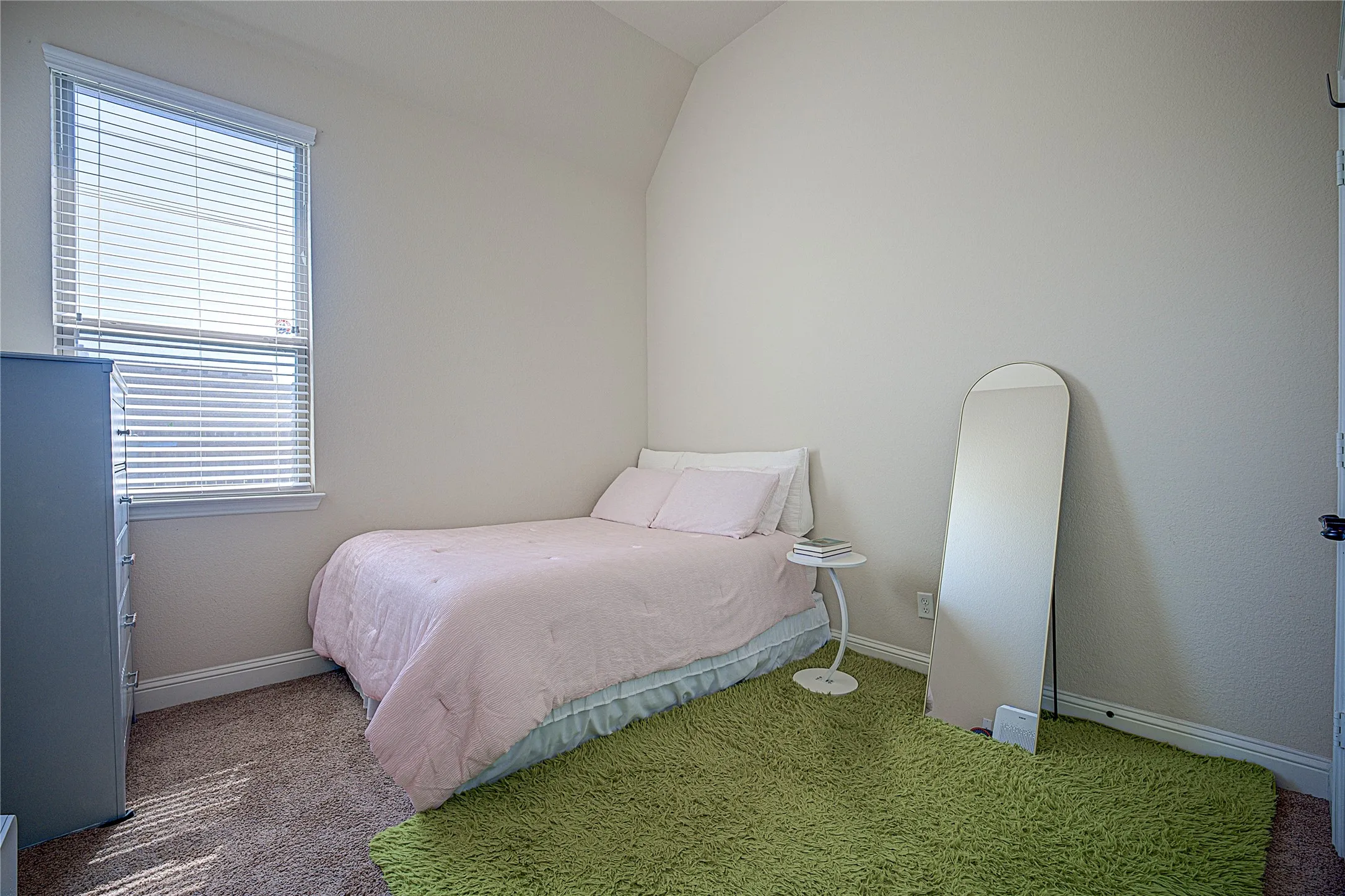 Carpeted flooring, vaulted ceiling, and a window with blinds