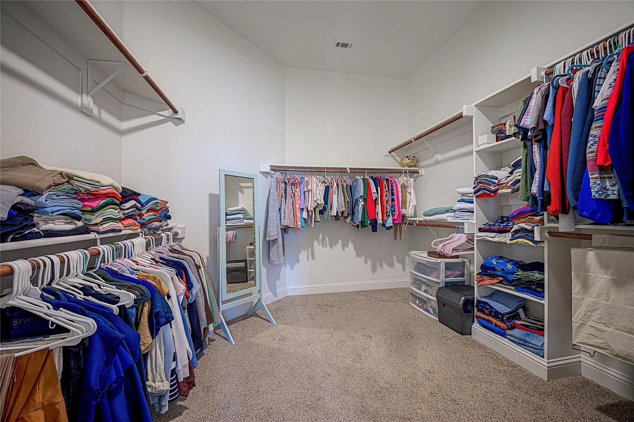 Spacious walk-in closet featuring multiple shelving units and hanging rods, built-in shelving, and carpet flooring