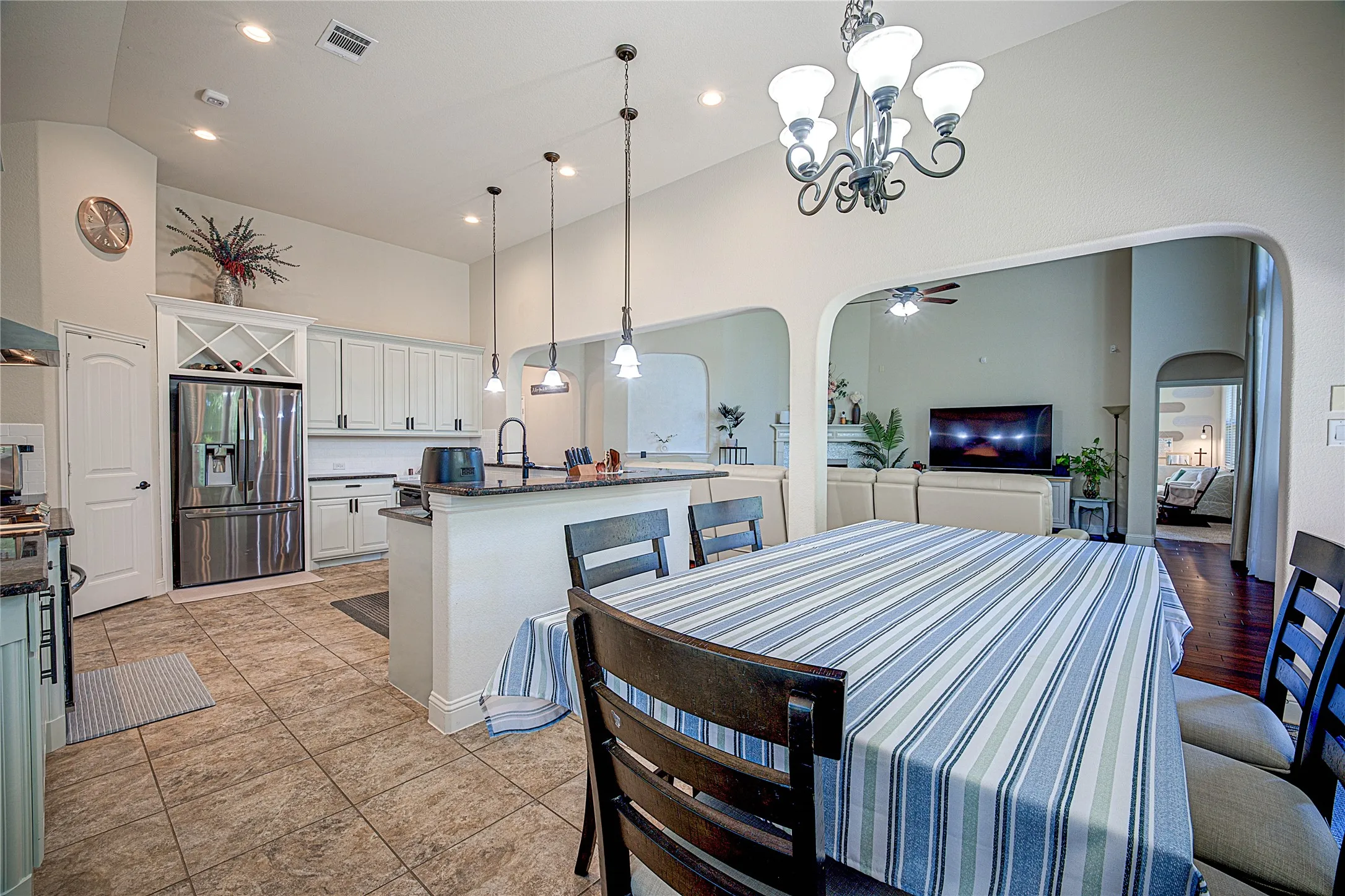 Kitchen with stainless steel refrigerator, white cabinetry, dark countertops, and pendant lighting