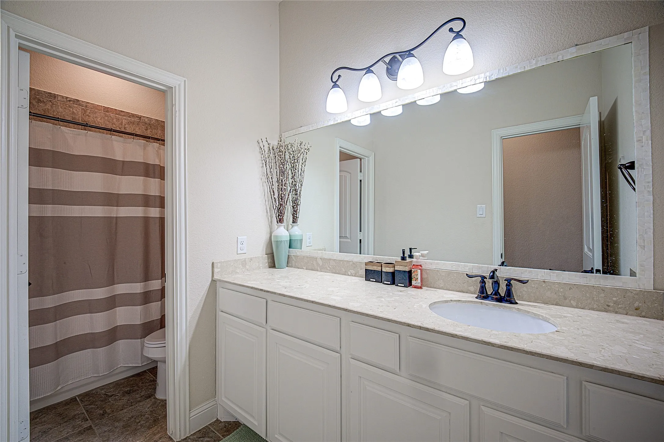 Dual white cabinetry vanity with integrated single sink and a broad mirror