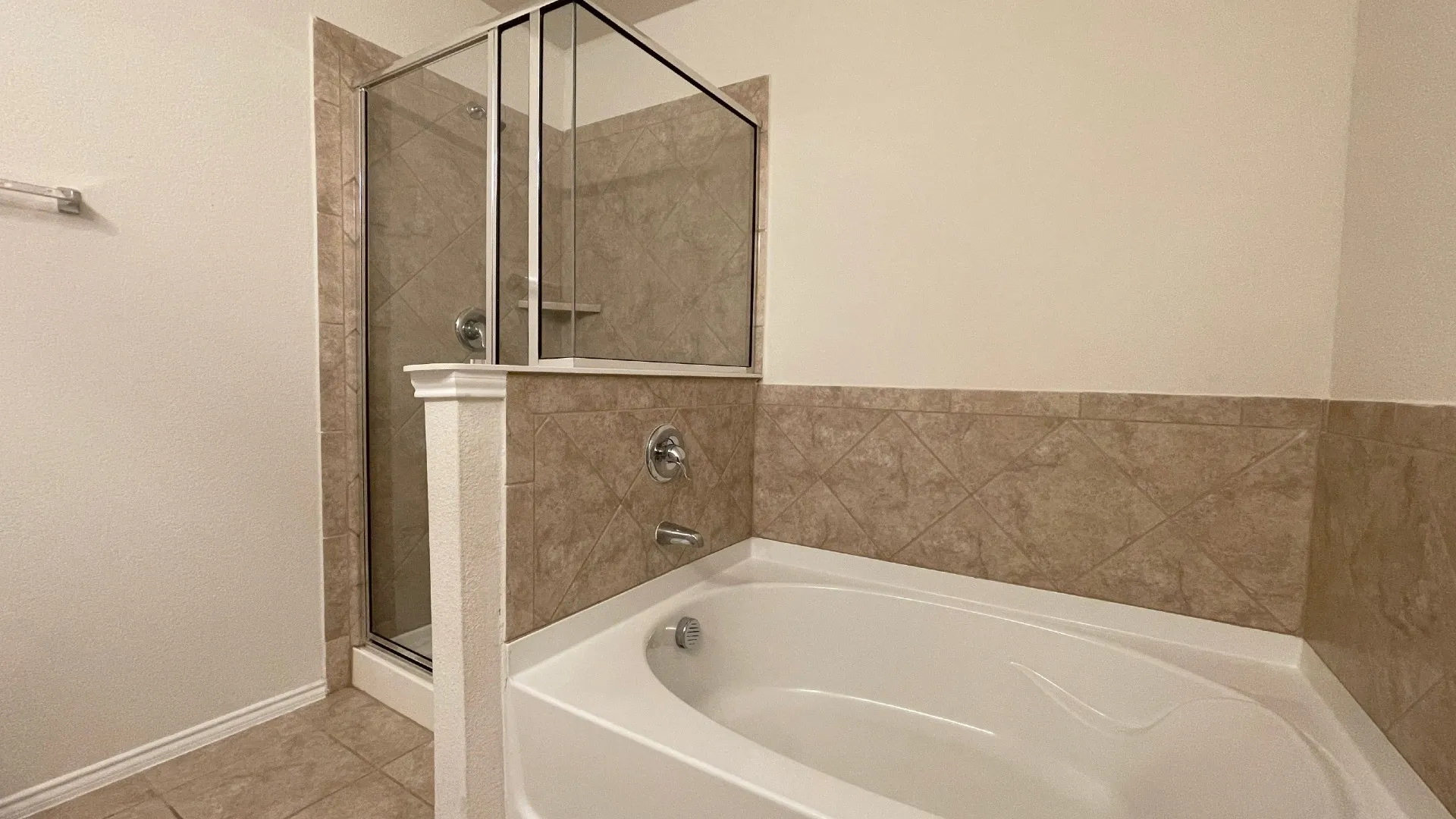 Tiled shower enclosure with a glass door, built-in bathtub, and matching tile wainscoting
