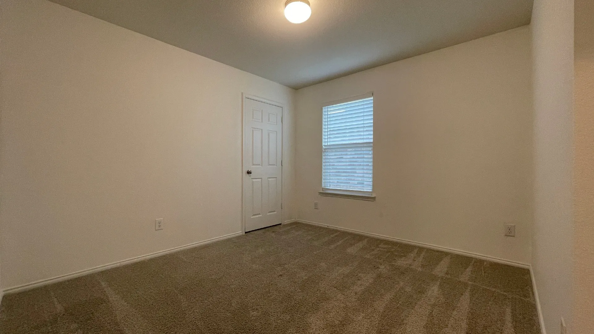 Neutral wall paint, light-colored carpeting, and a window with blinds