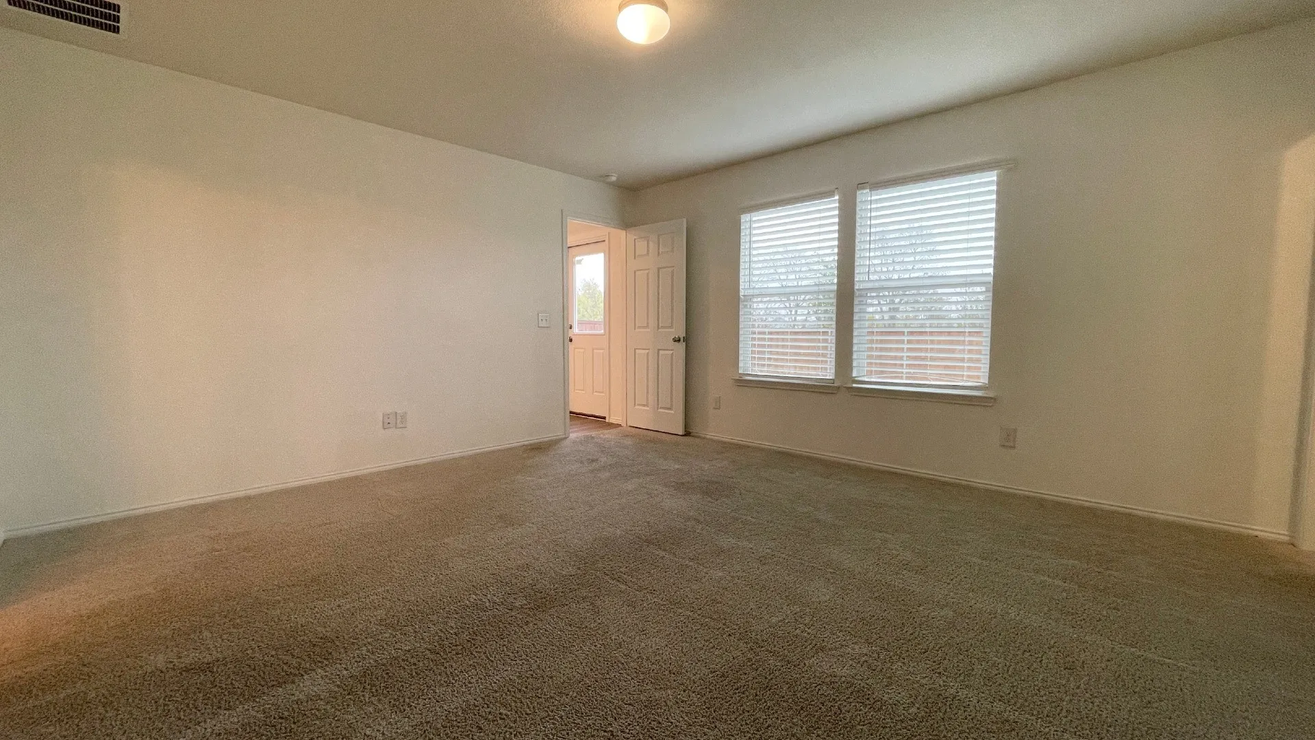 Spacious room featuring neutral wall finishes, recessed ceiling lighting, carpet flooring, and dual windows with plantation shutters providing natural light