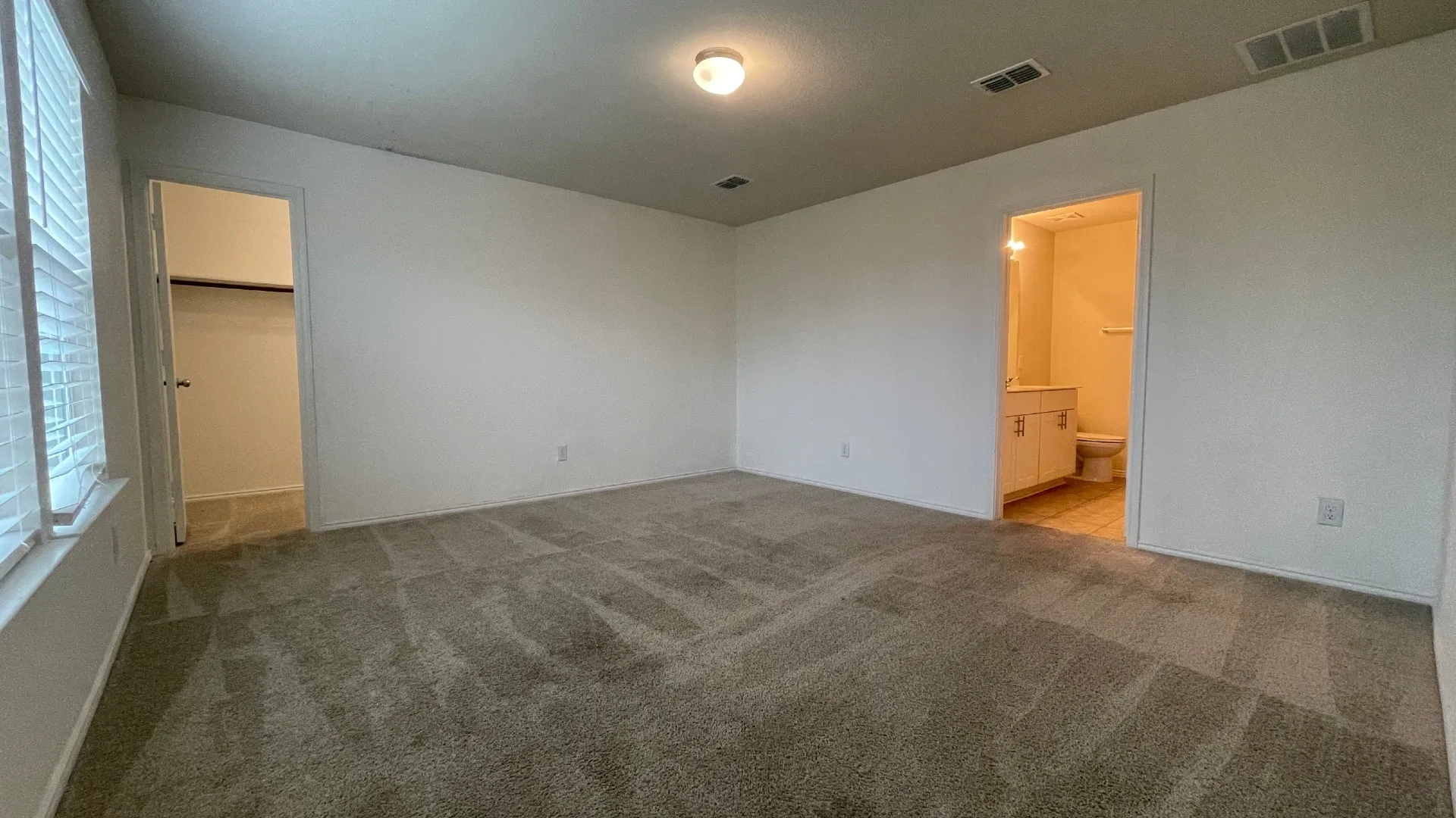Spacious interior room featuring neutral wall finishes, recessed ceiling lighting, and neutral-toned carpeting throughout