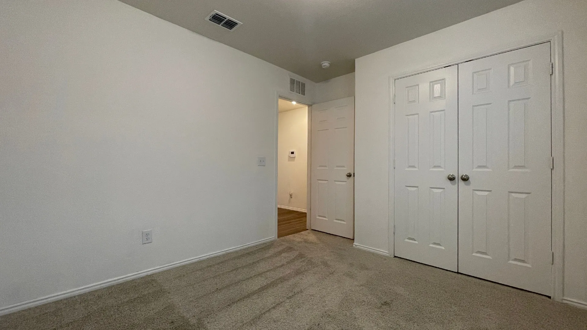 Spacious bedroom with neutral wall finishes, plush carpeting, and abundant natural light