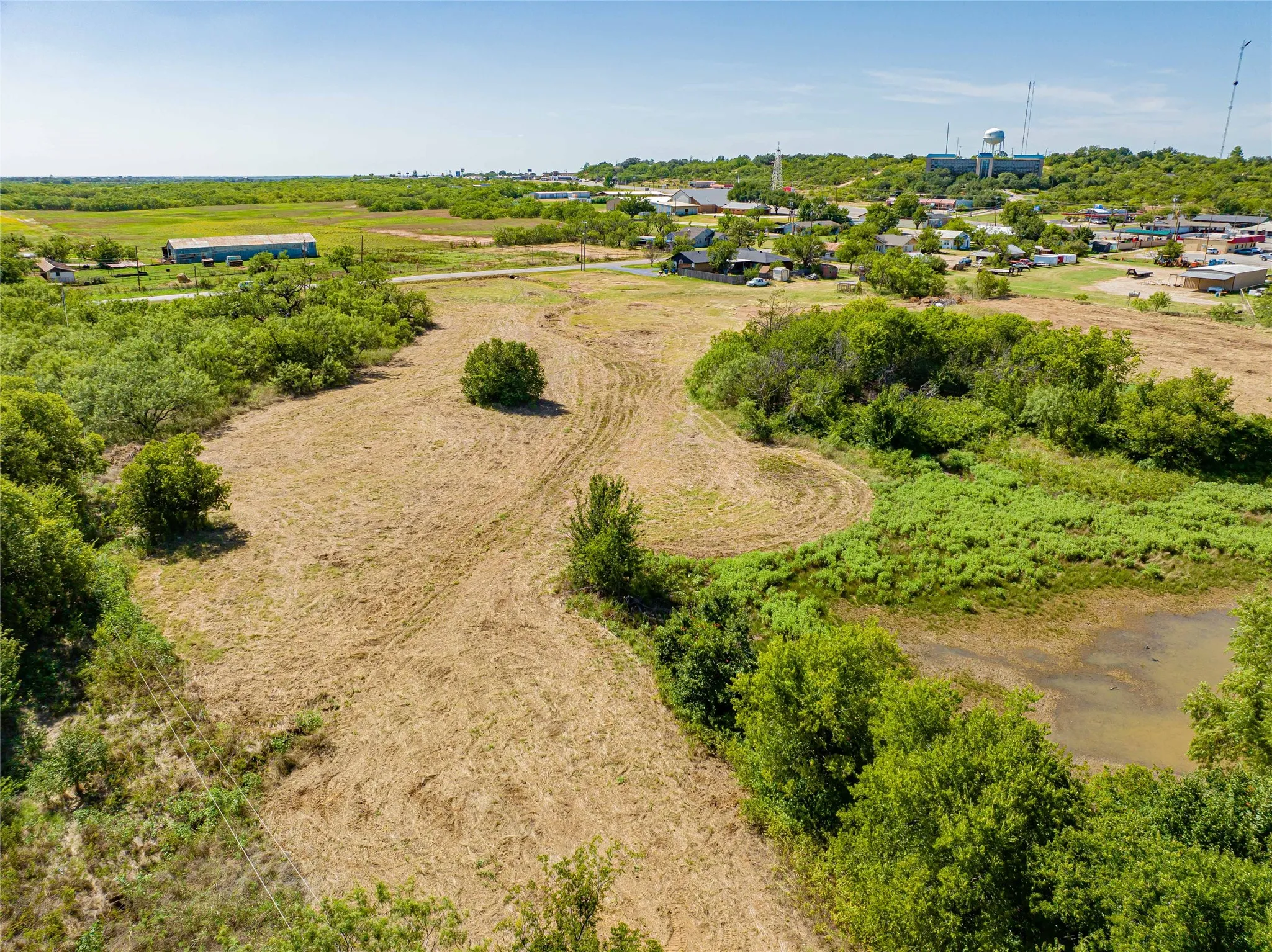 Expansive rural acreage featuring gently rolling terrain with mature tree clusters and natural water features