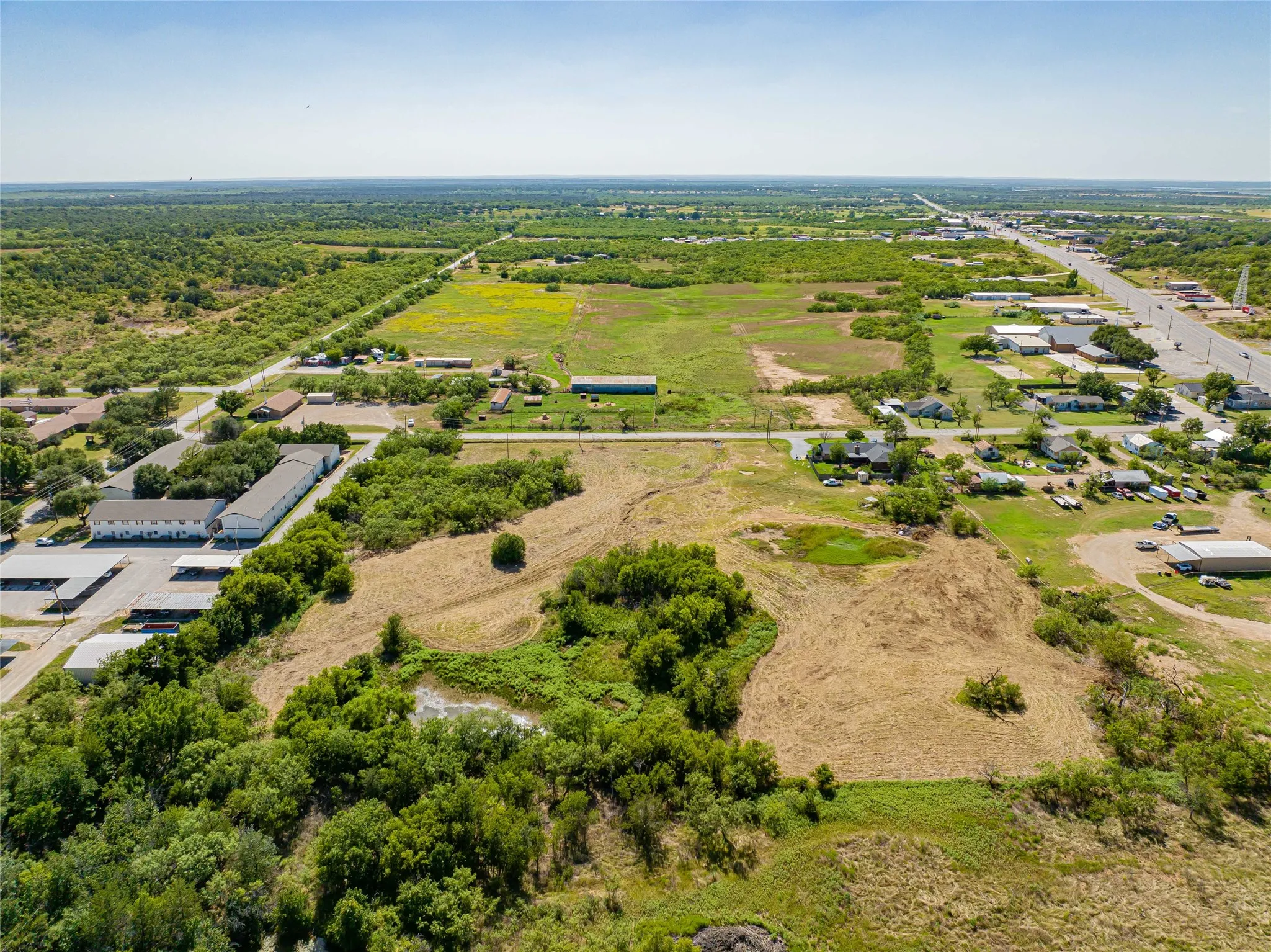 Expansive land parcel featuring varied terrain with sections of open pasture, natural vegetation, and scattered trees