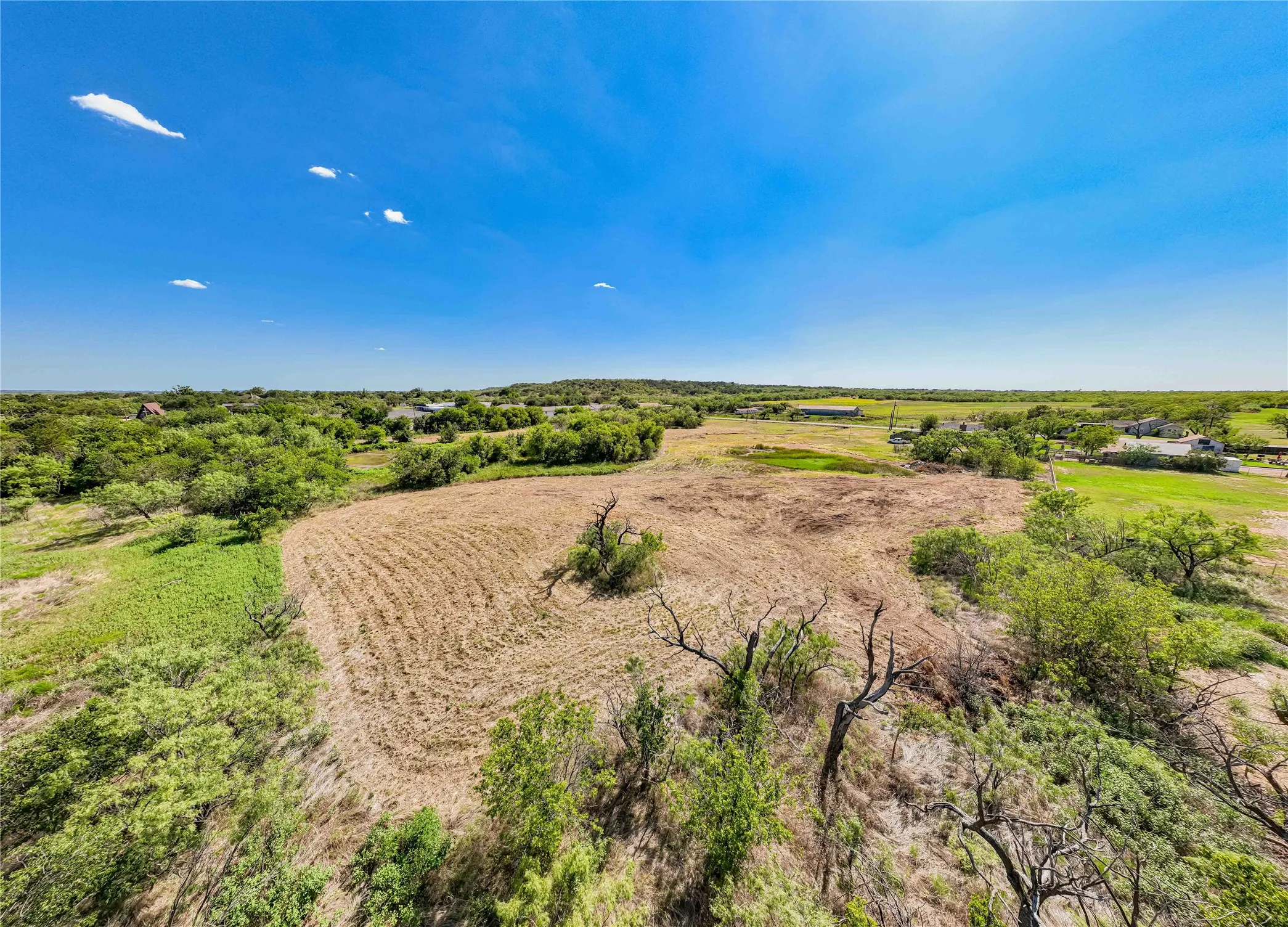 Expansive land parcel featuring open fields and surrounding mature trees