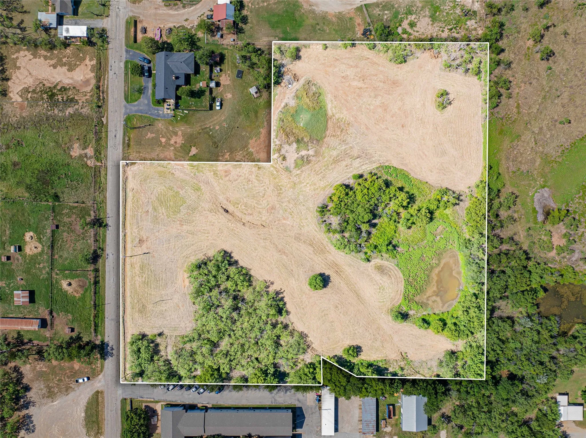 Expansive cleared lot with mature tree clusters and natural vegetation, offering substantial development potential