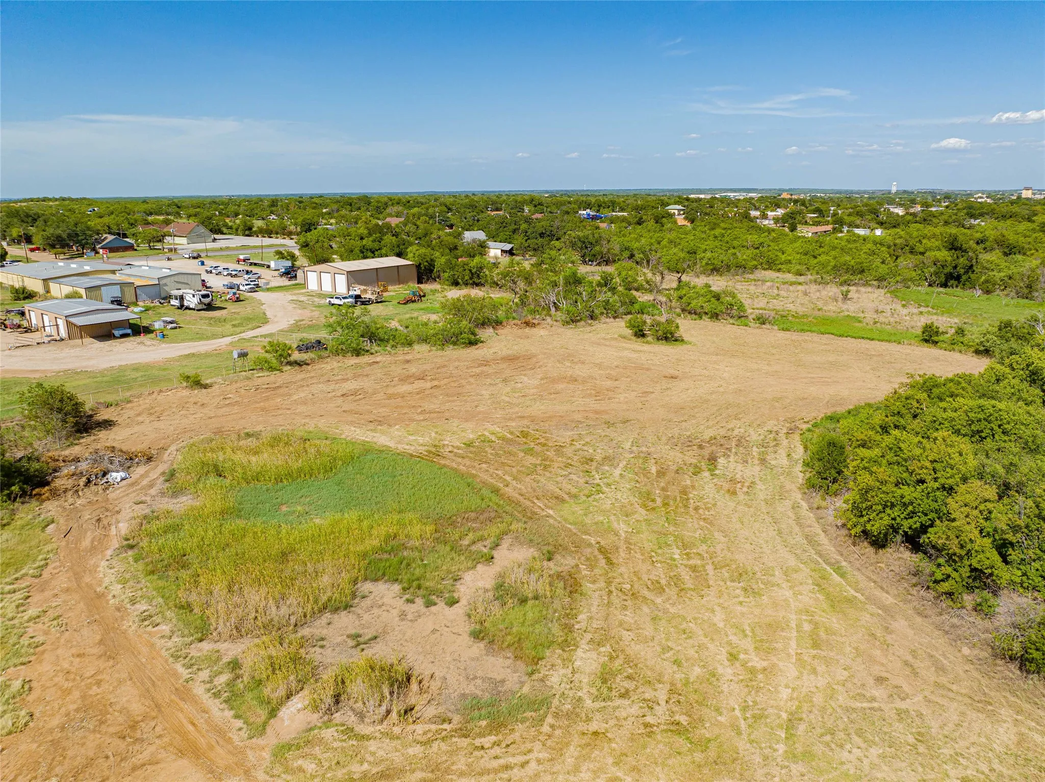 Expansive cleared land with surrounding mature trees and natural vegetation