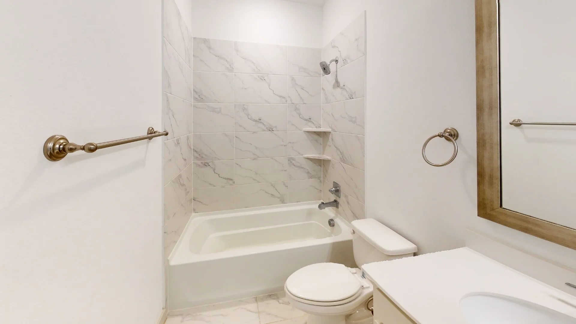 Bathtub with tile surround, built-in shelving, and a shower head