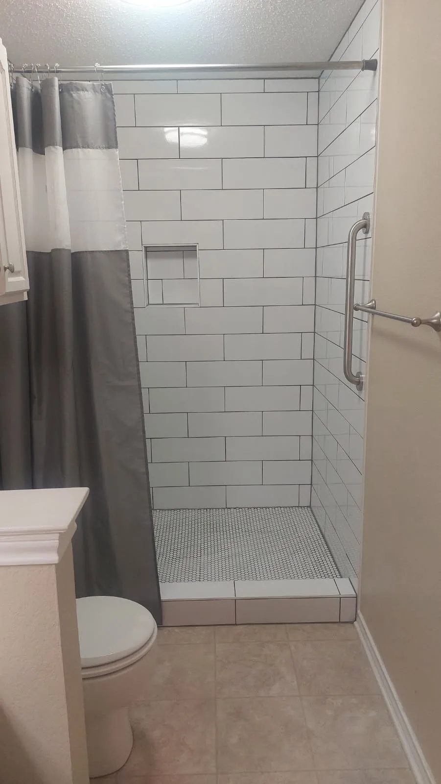 Walk-in shower with subway tile surround, integrated shower niche, penny tile floor,